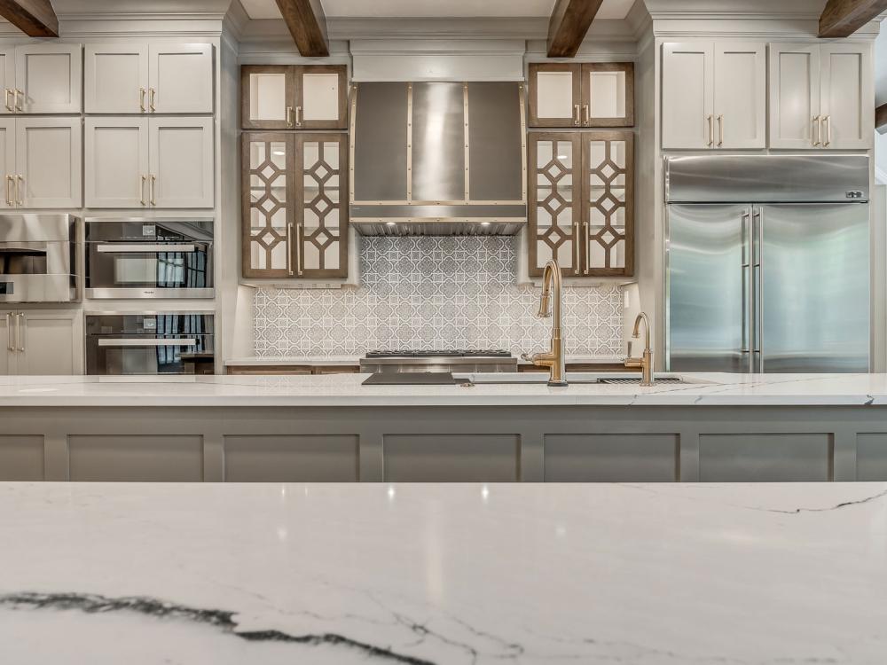 Stainless steel range hood centered between patterned glass cabinet doors in a modern kitchen.