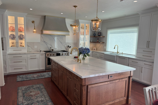 Sleek metal range hood with gold trim in a bright white kitchen.