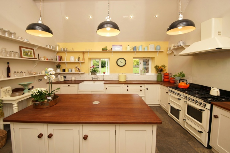 Charming farmhouse kitchen with white cabinets, wooden countertops, and pendant lighting.