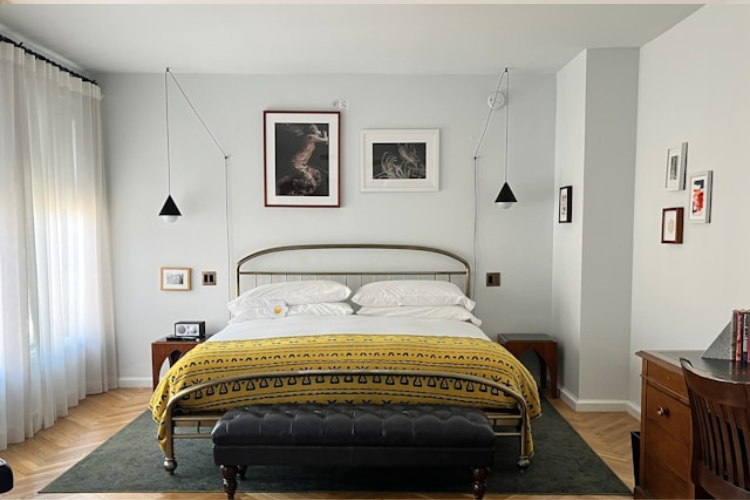 Modern bedroom interior with a brass bed frame and patterned yellow throw.