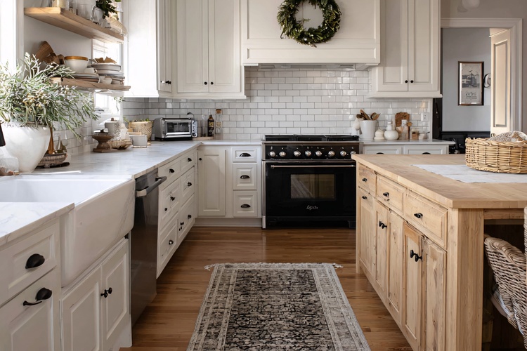 Modern farmhouse kitchen interior with white cabinets, wood island, and open shelving.