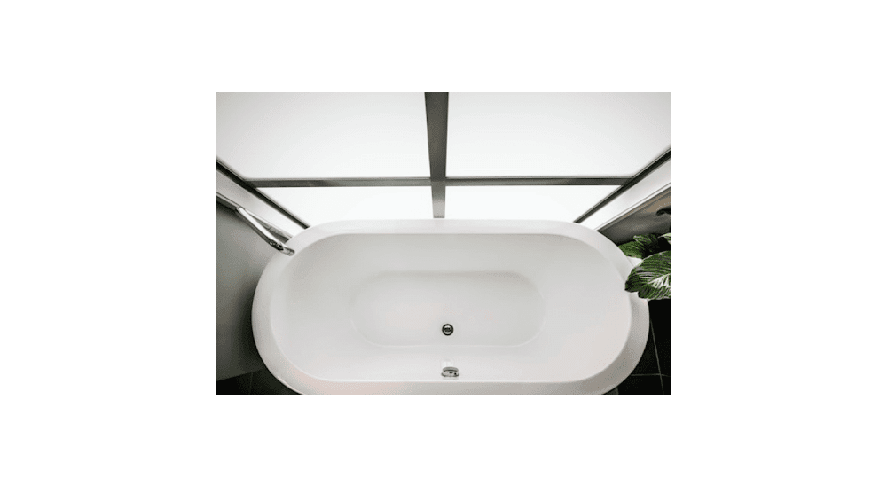 Freestanding white bathtub in a modern bathroom with large windows