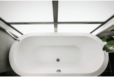 Freestanding white bathtub in a modern bathroom with large windows