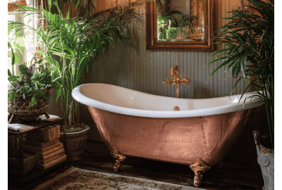 Luxury bathroom featuring a copper clawfoot bathtub surrounded by lush plants.