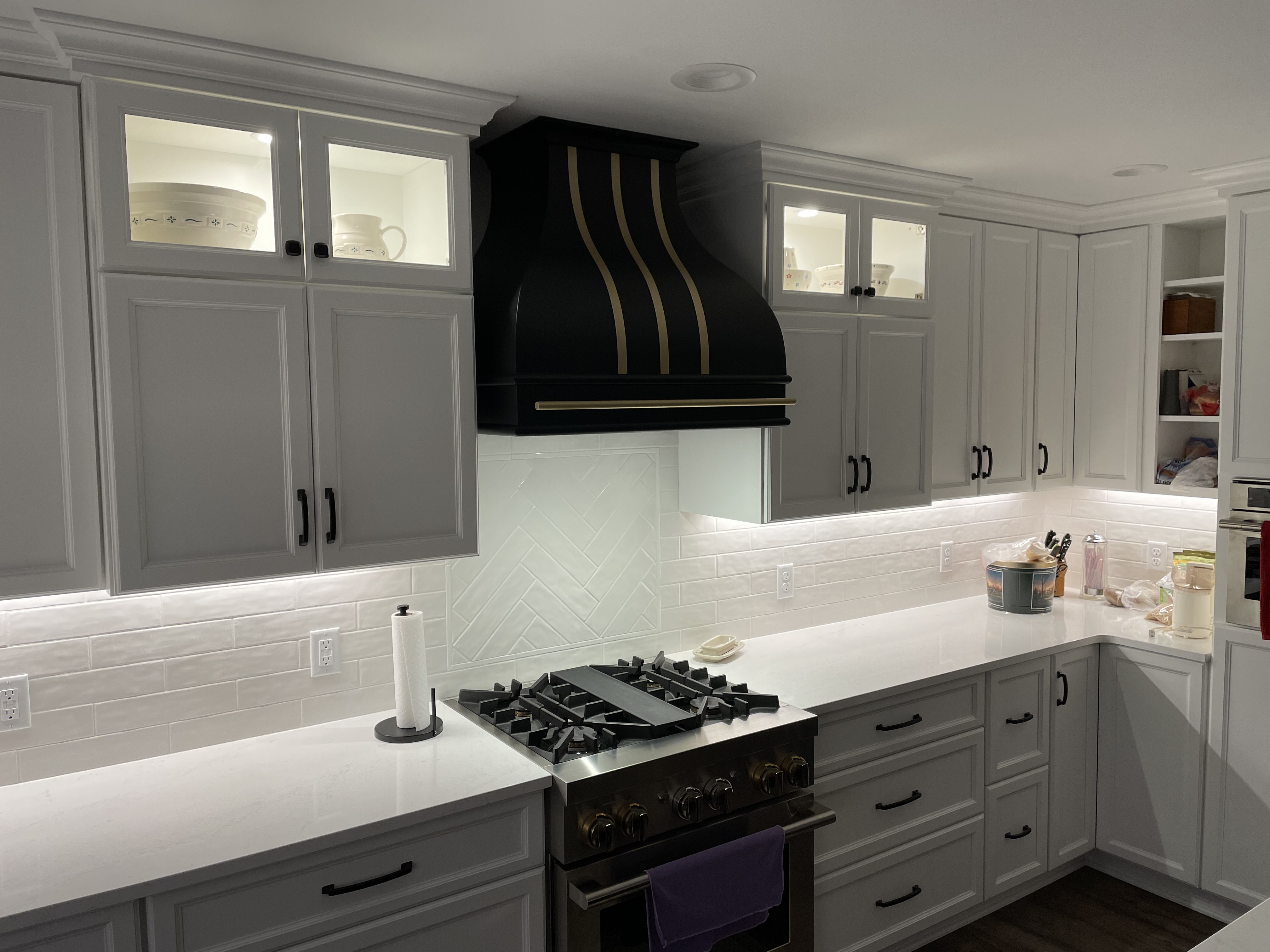 A classic kitchen design with white kitchen cabinets and countertops, featuring a stylish range hood charming brick backsplash