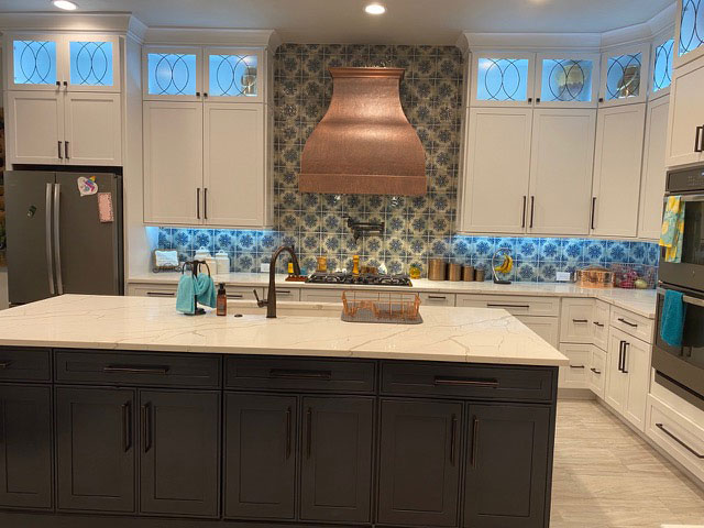 A copper range hood that complements the cottage kitchen style, along with elegant white kitchen cabinets and marble kitchen countertops