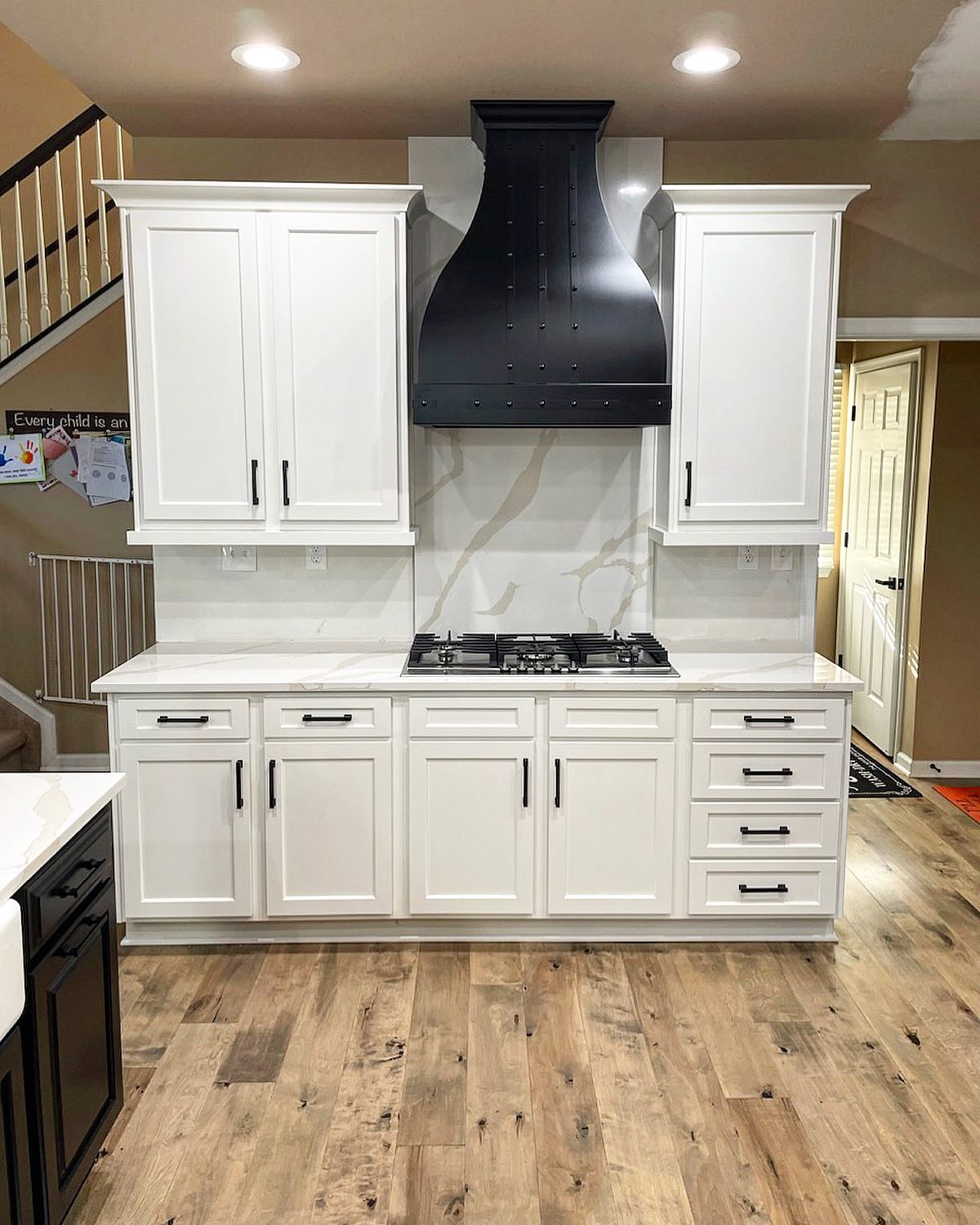 French-inspired kitchen design idea featuring white kitchen cabinets, marble kitchen countertops, stunning marble backsplash, chic range hood