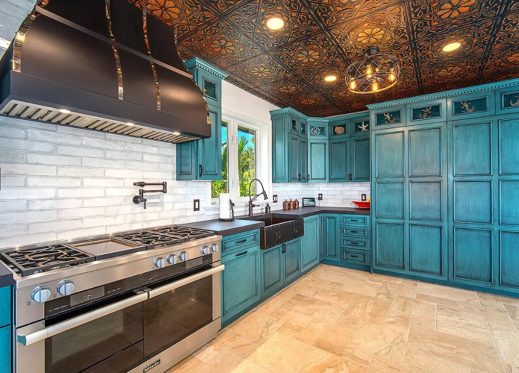 CopperSmith Artisan AT5 Wall Mount Stainless Steel Black Enamel Kitchen Range Hood in a Costal Style Kitchen features Blue Cabinets Black countertops and white brick backsplash