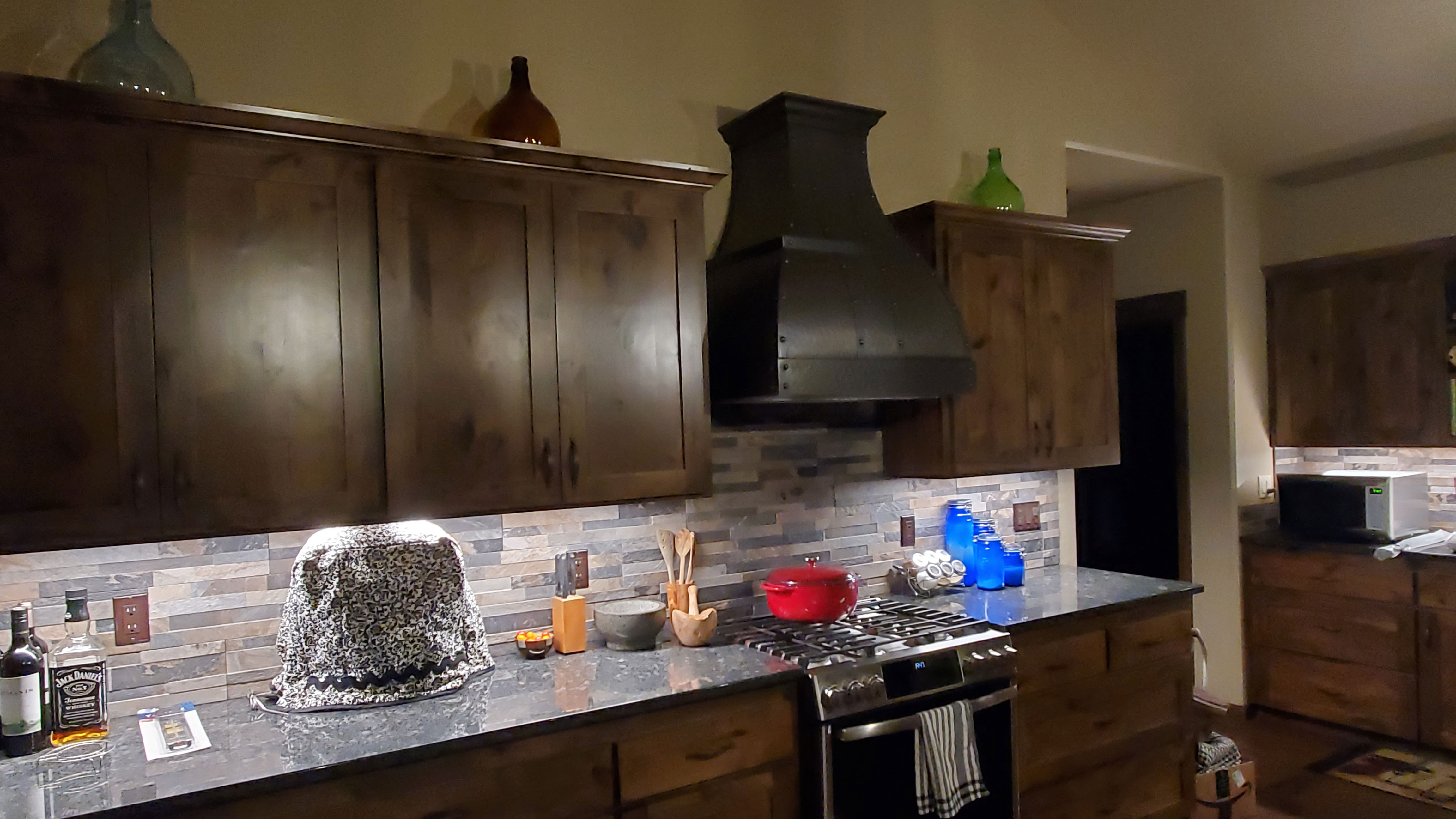 Copper range hood with brown kitchen cabinets paired with a stunning marble backsplash or a rustic brick backsplash