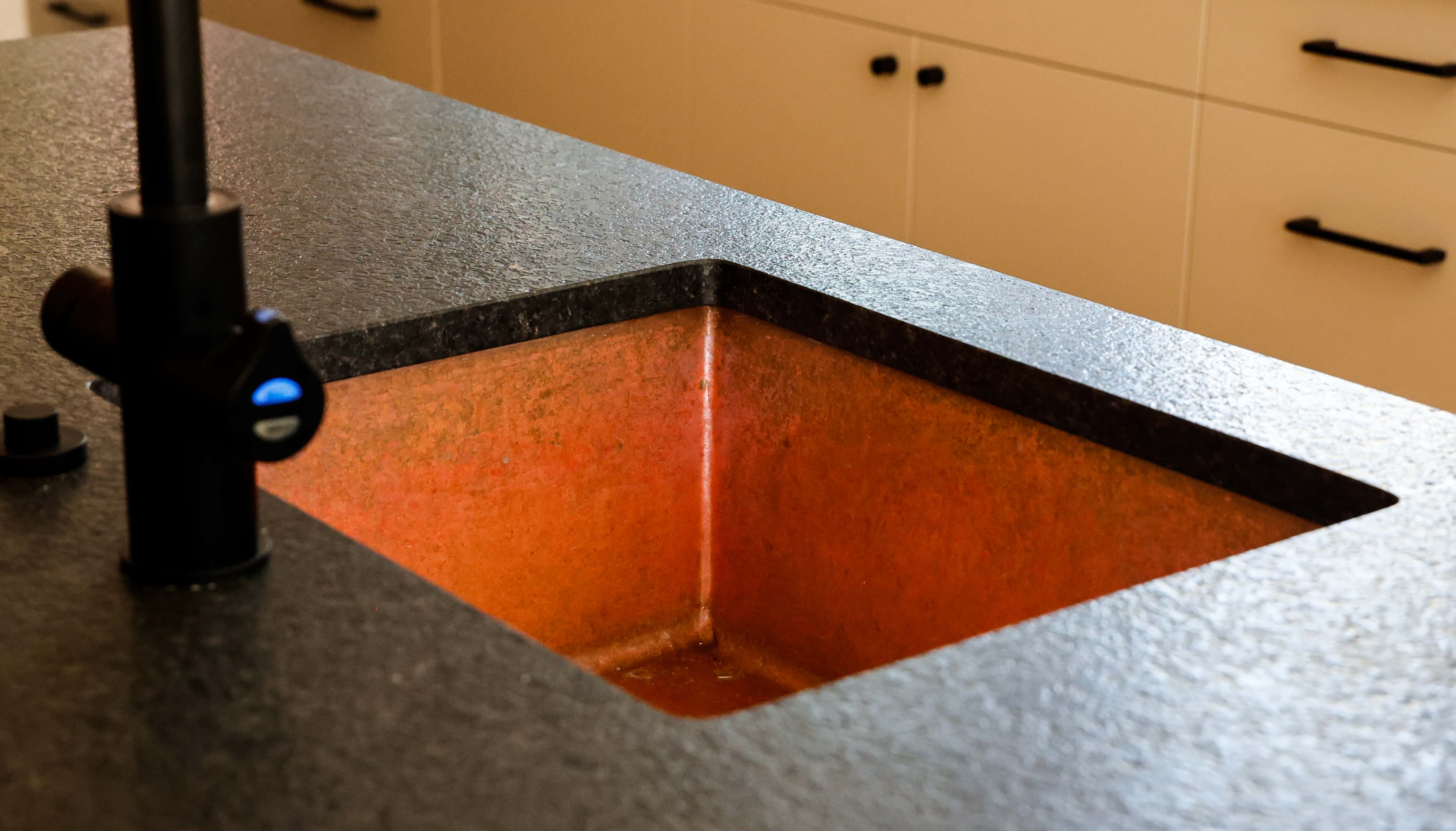 CopperSmith Bar SB Weathered Copper Sink in a contemporary kitchen with Black countertops and white cabinets