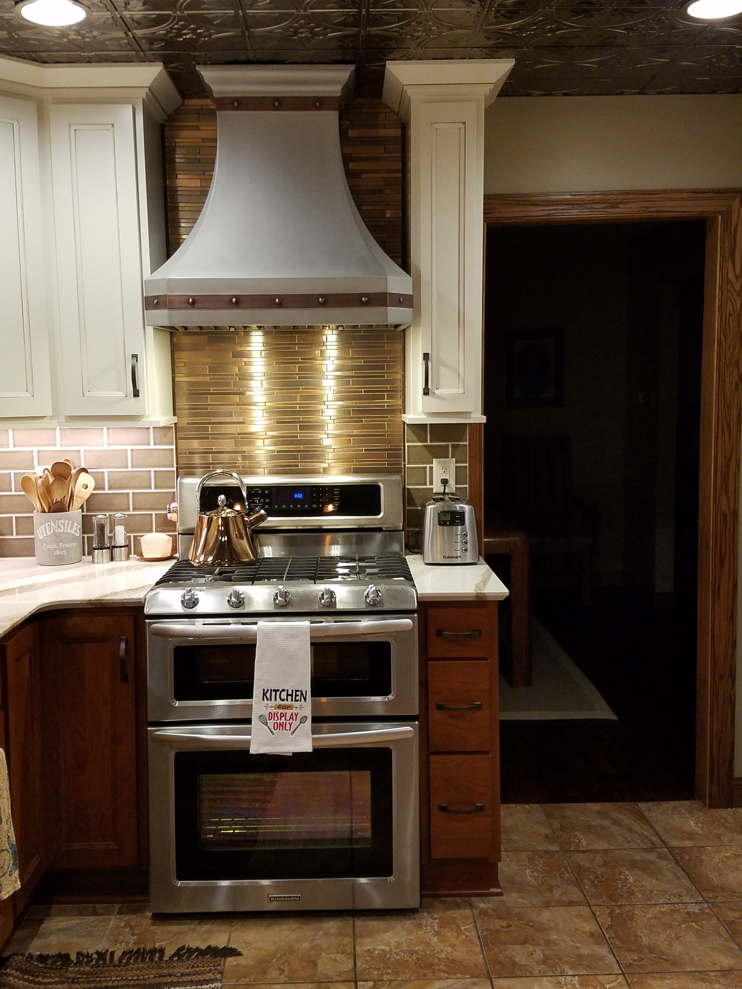 Trending kitchen design idea with range hood design features brown kitchen cabinets, marble kitchen countertops stylish marble backsplash