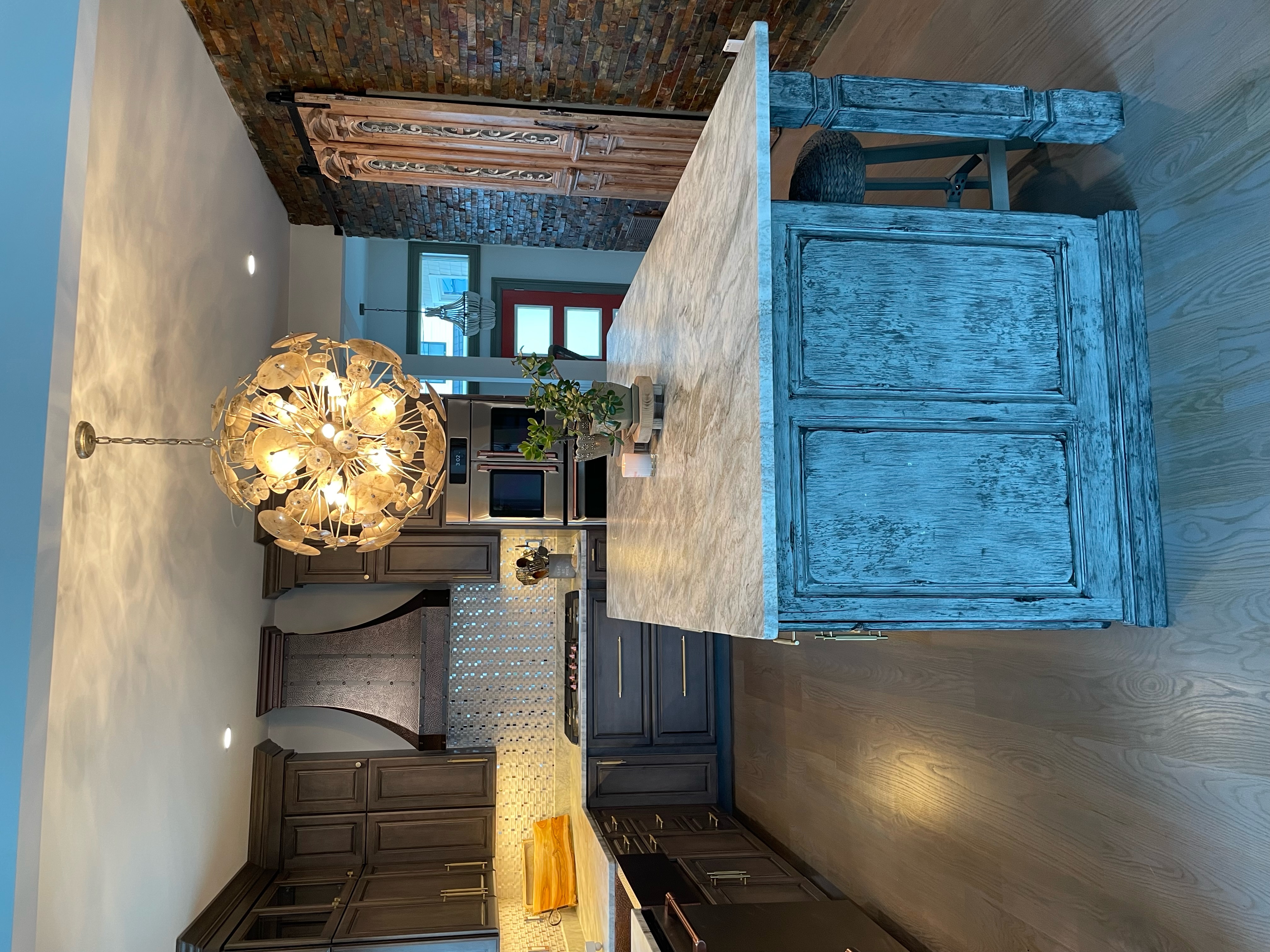 Charming kitchen design idea cottage-inspired touch, featuring brown kitchen cabinets, kitchen countertops, stunning marble backsplash, creative kitchen table idea