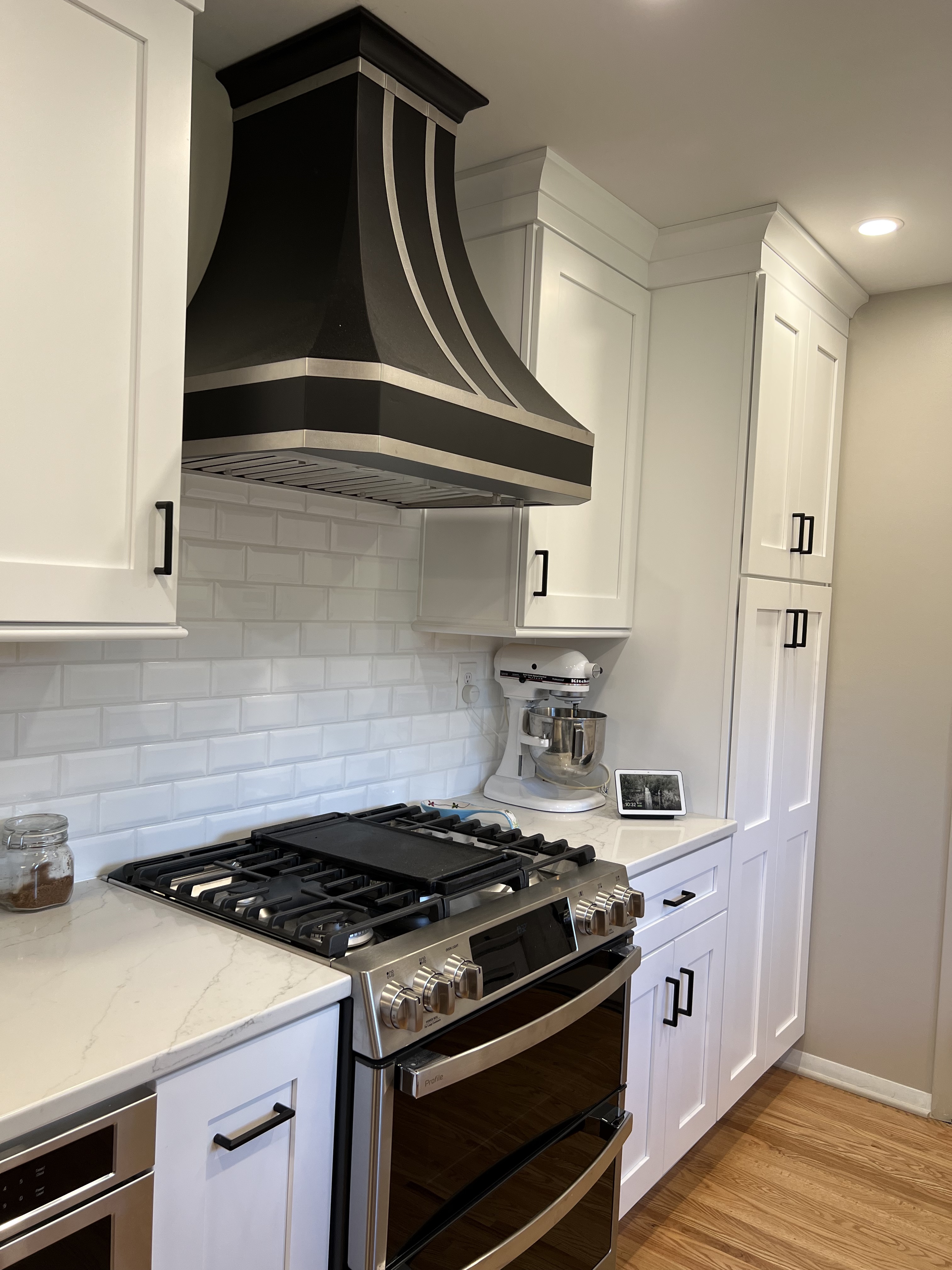 Stunning design idea french-inspired , featuring white kitchen cabinets, black kitchen countertops, and white tile backsplash, with stylish range hoods,