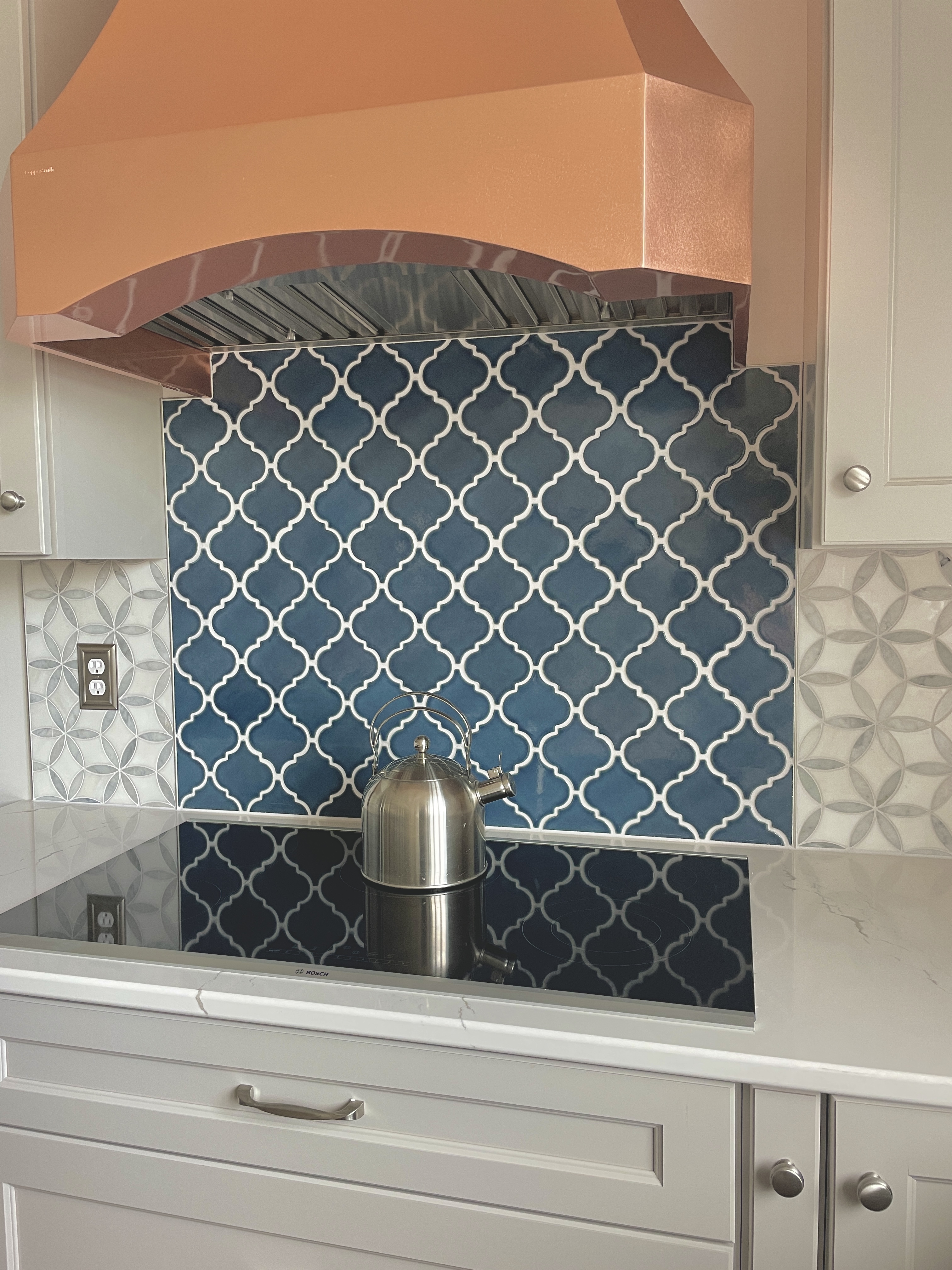 Kitchen design idea, including french-inspired aesthetics, with white kitchen cabinets, white kitchen countertops, and marble backsplash,stylish range hood options
