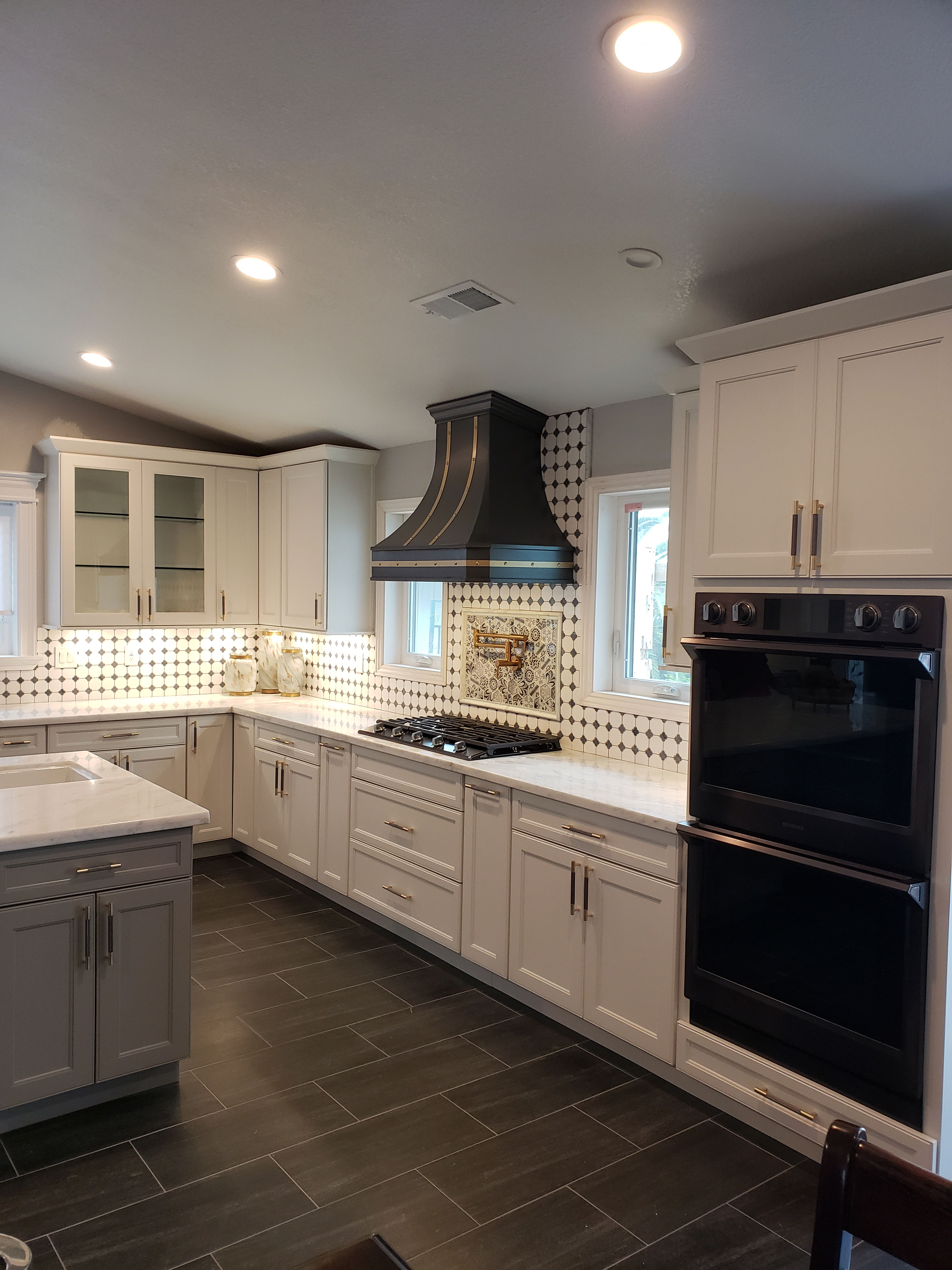 Black range hood in white kitchen with windows and checkered backsplash World CopperSmith
