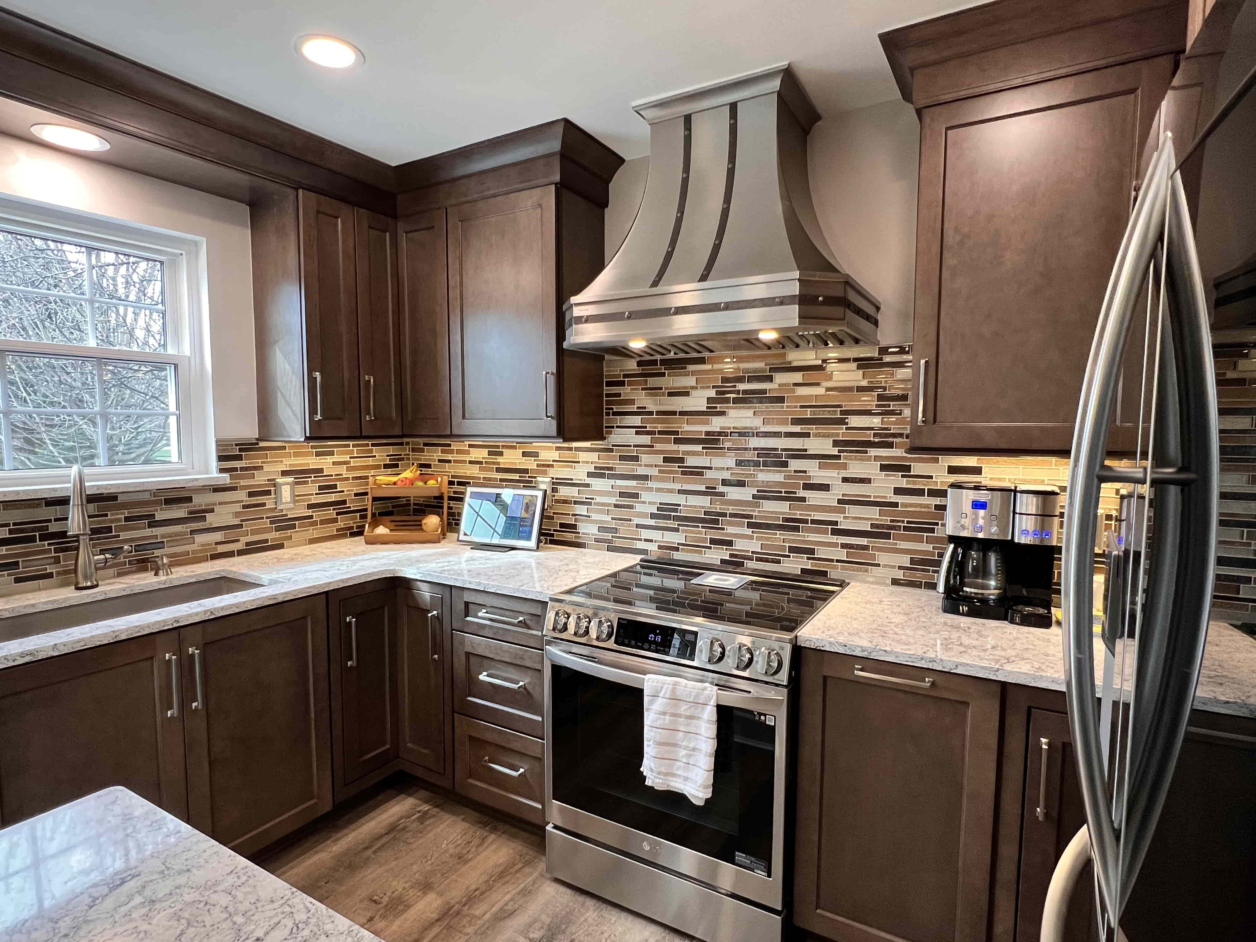 French-inspired design with sleek brown cabinets, luxurious marble countertops, marble backsplash, all crowned by a stunning range hood