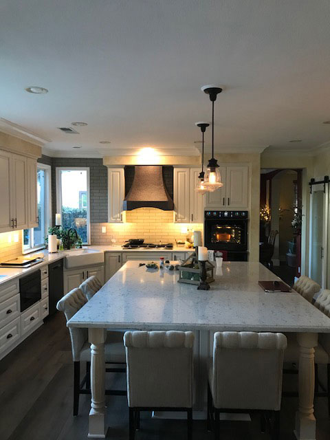 Kitchen table design with white cabinets,marble countertops, charming brick backsplash,