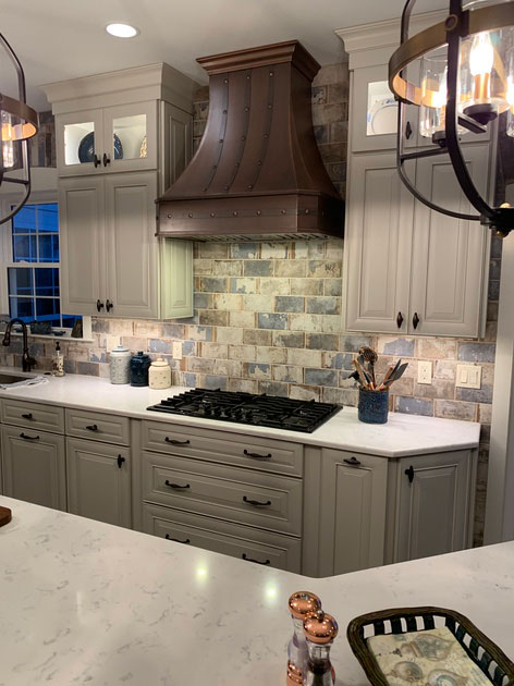 Kitchen design idea with white cabinets,marble countertops, stunning brick backsplash with range hood
