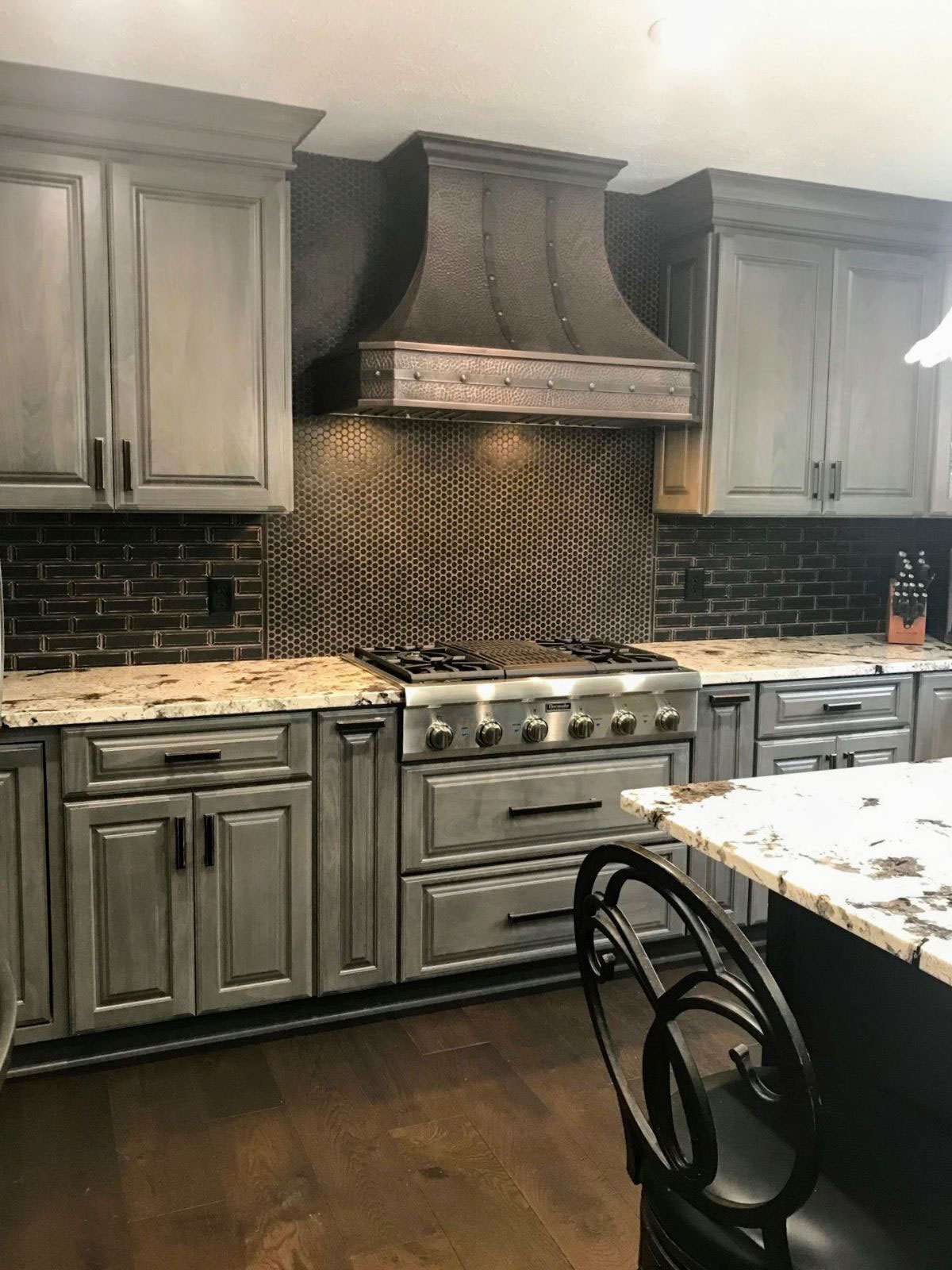 French kitchen design with grey cabinets,marble countertops, captivating brick backsplash, while exploring range hood