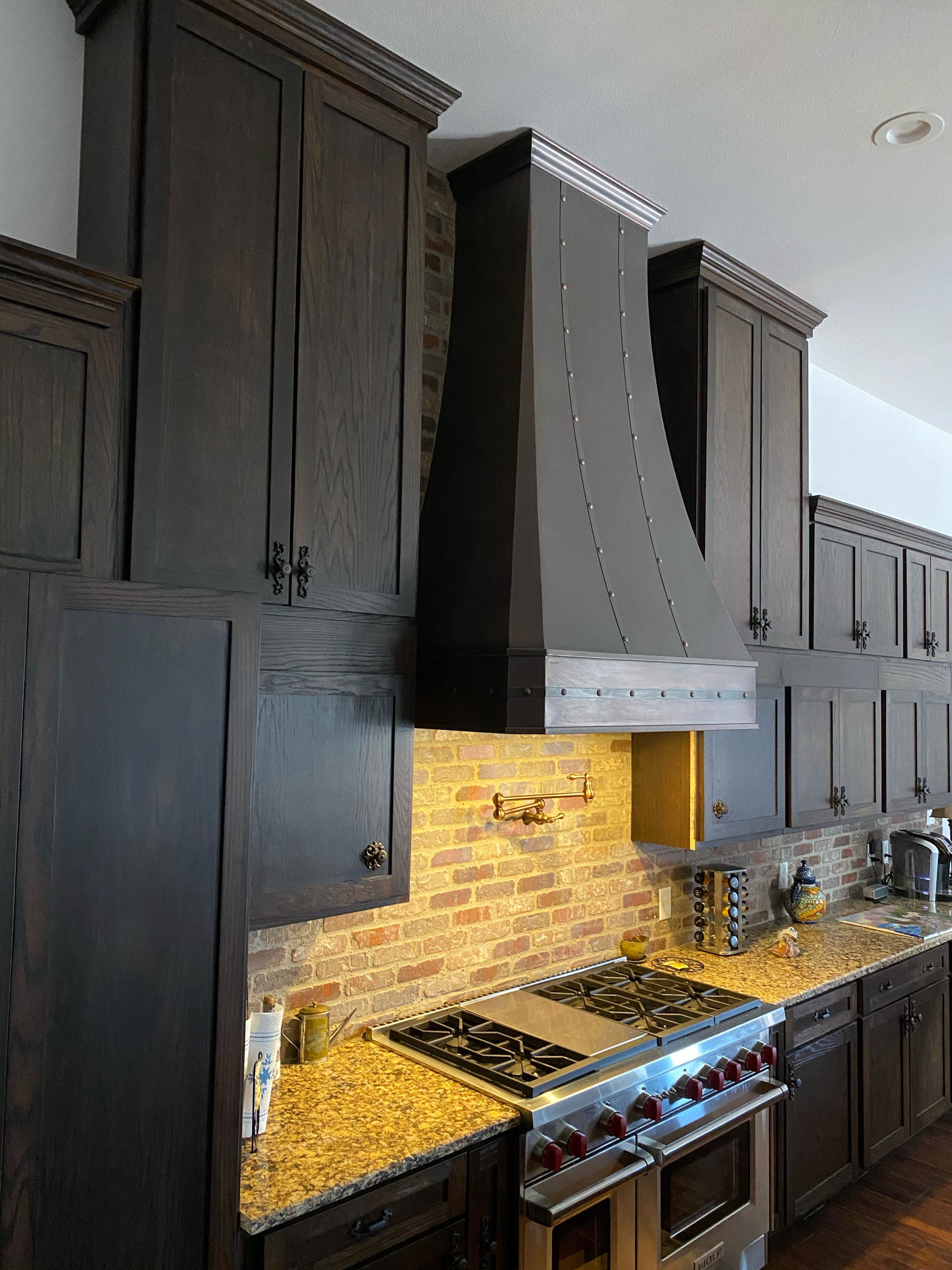 Attractive cottage-kitchen design with brown cabinets,marble countertops, luxurious marble backsplash with range hood