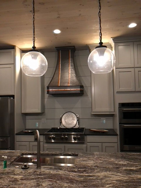 Black range hood with copper belts in white and black kitchen World CopperSmith