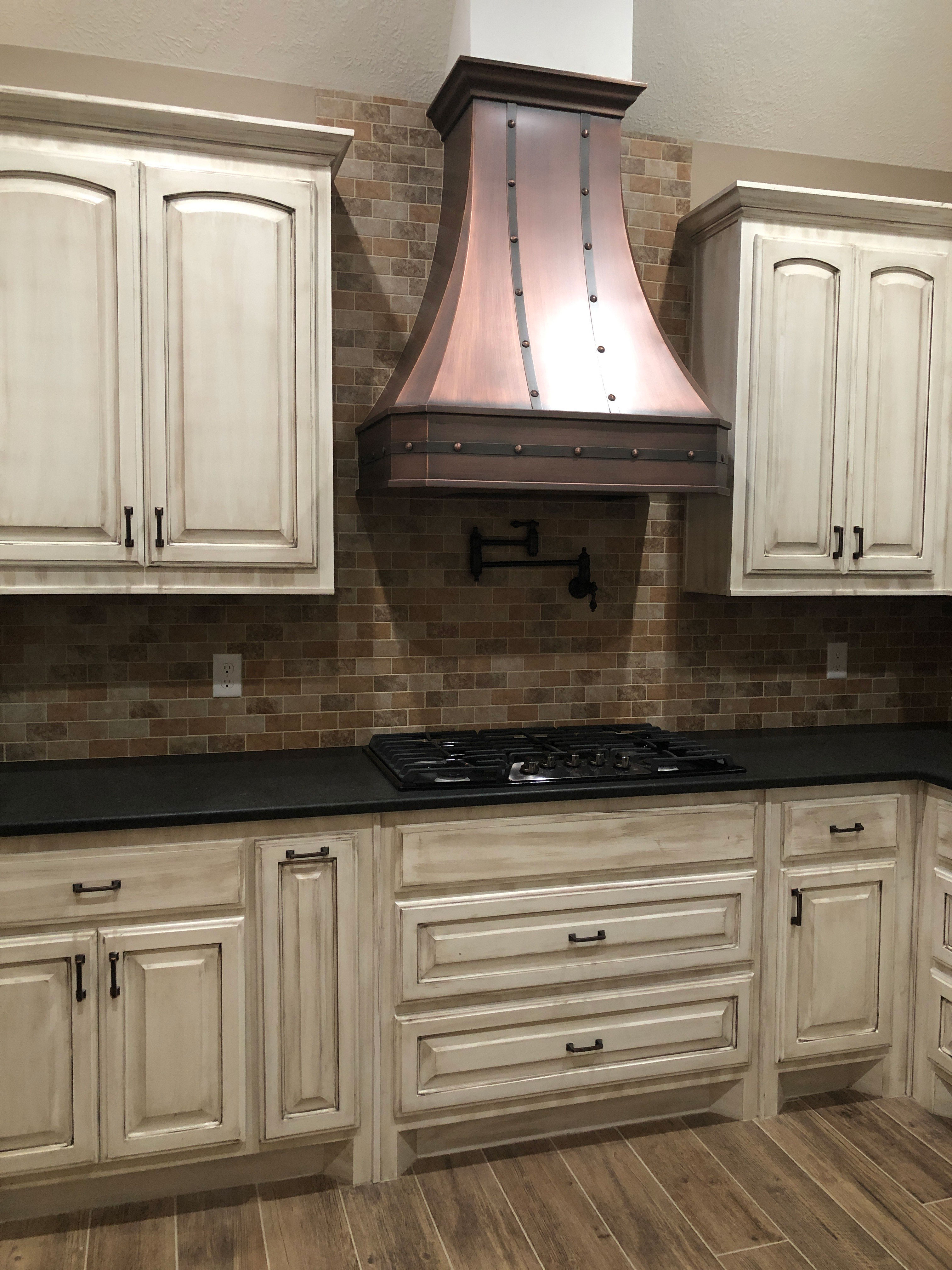 French kitchen design with white cabinets, stylish grey kitchen countertops, captivating brick backsplash with range hood