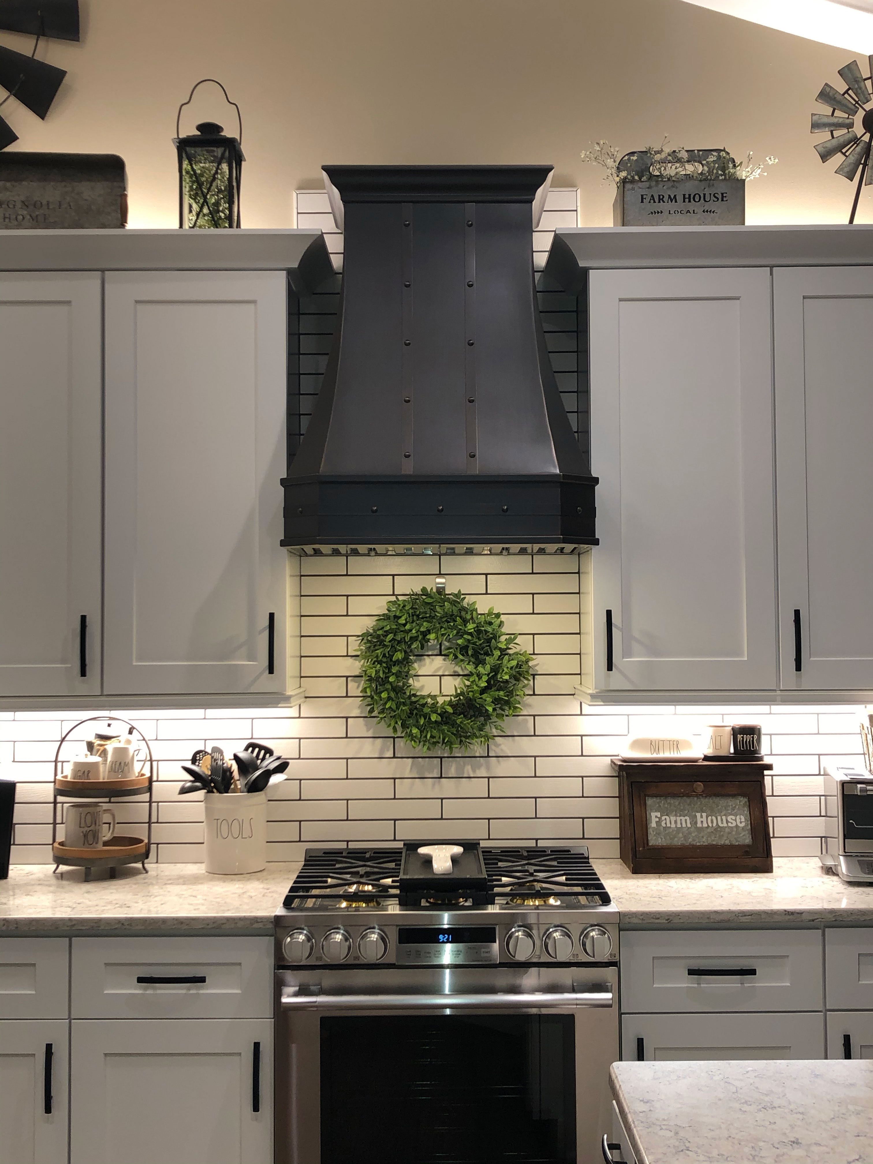 Experience french kitchen design with white cabinets, elegant grey kitchen countertops, captivating brick backsplash with range hood