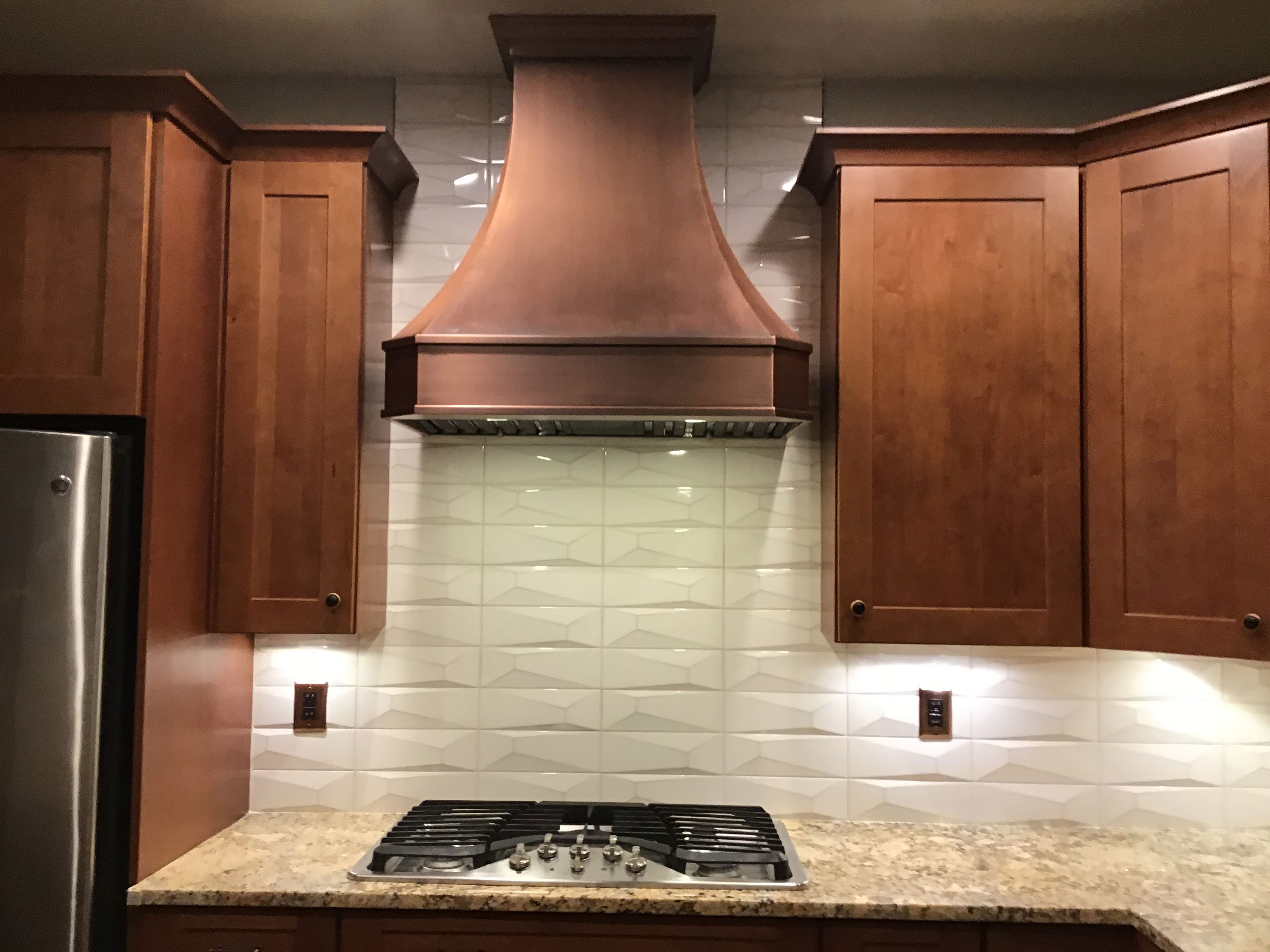Discover cottage kitchen design idea with range hood, featuring rich brown cabinets, luxurious marble countertops, brick backsplas