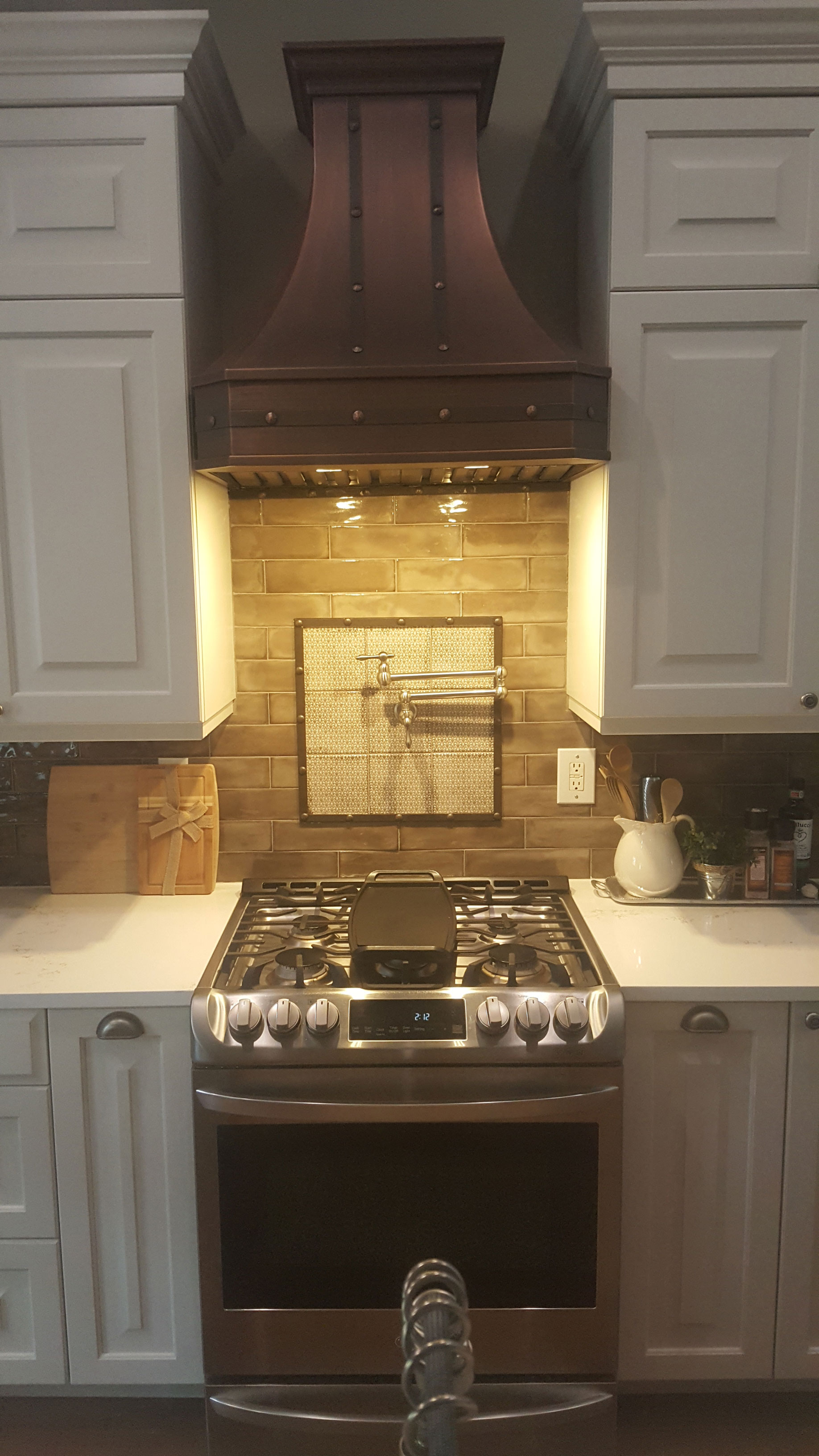 Unleash french-inspired kitchen design idea with copper range hood, white cabinets with grey kitchen countertops captivating brick backsplash