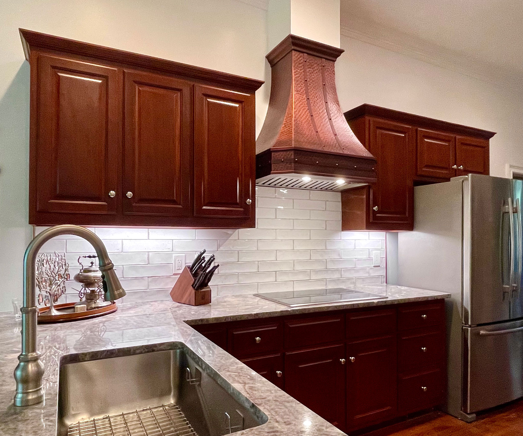 Embrace cottage kitchen design with rich brown kitchen cabinets,marble kitchen countertops with range hood charming brick backsplash