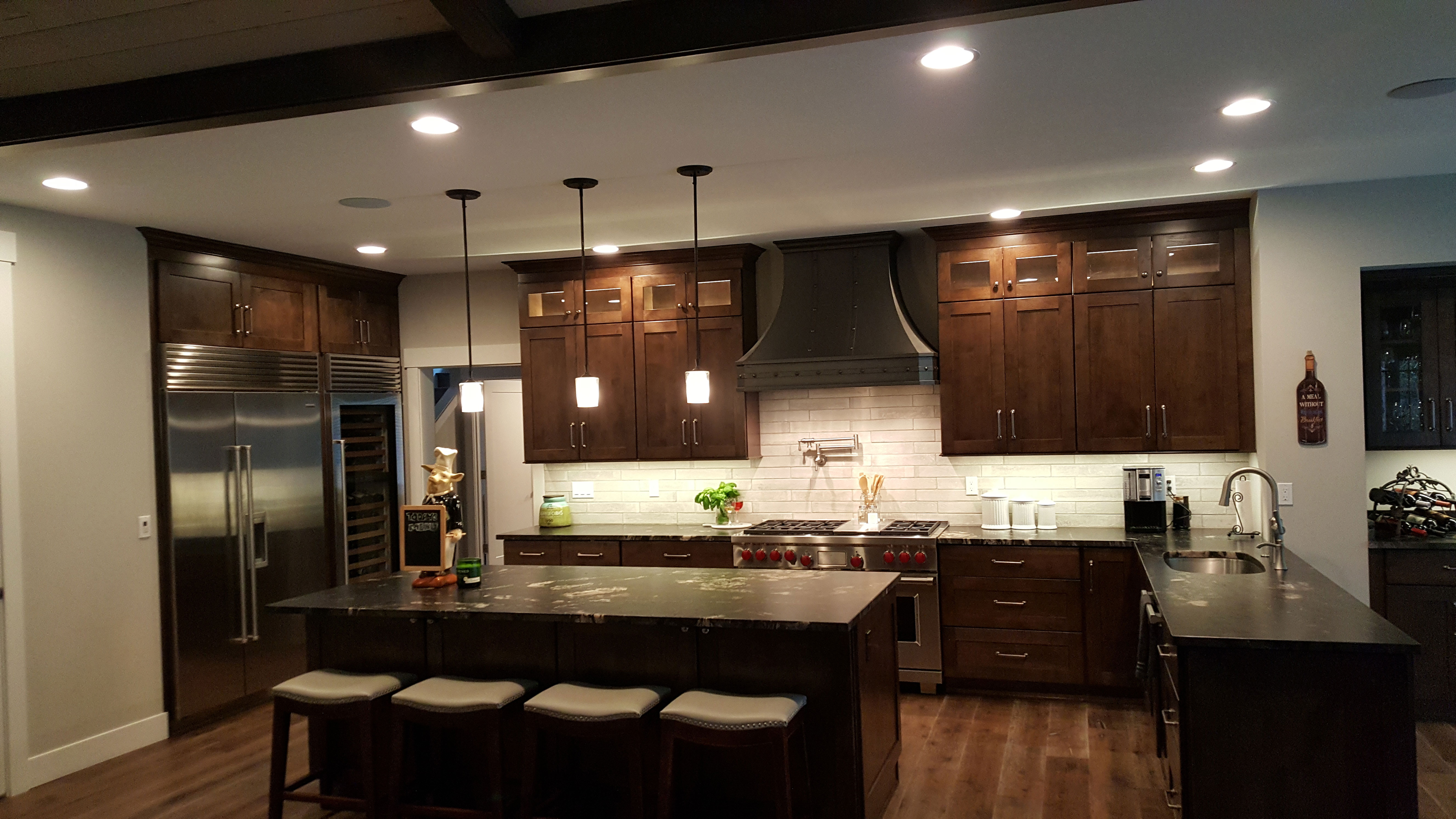 Enhance your traditional kitchen with creative range hood brown kitchen cabinets, black kitchen countertops and stylish brick backsplash