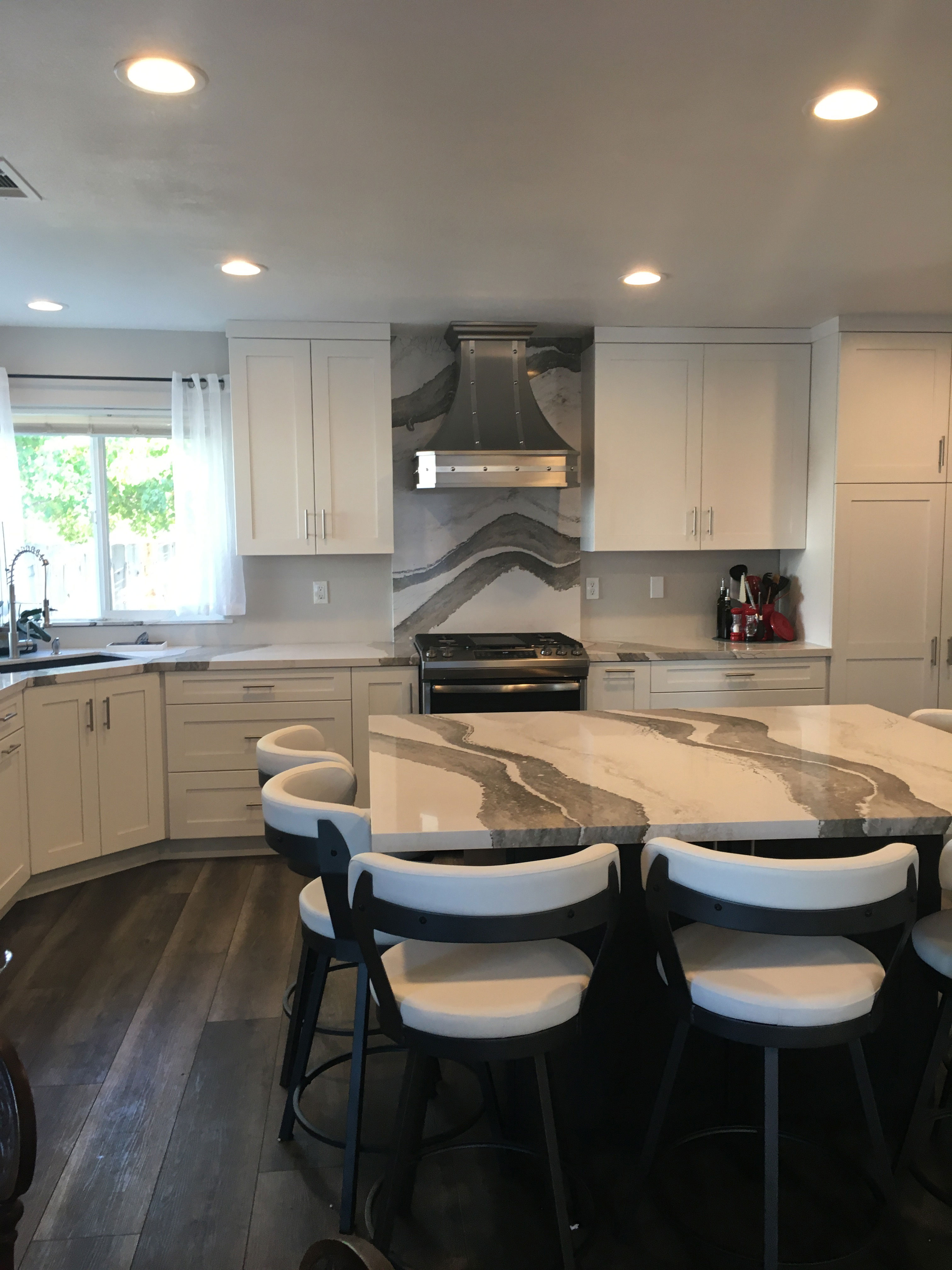 Beautiful kitchen planning with range hood, white kitchen cabinets, marble kitchen countertop and backsplash