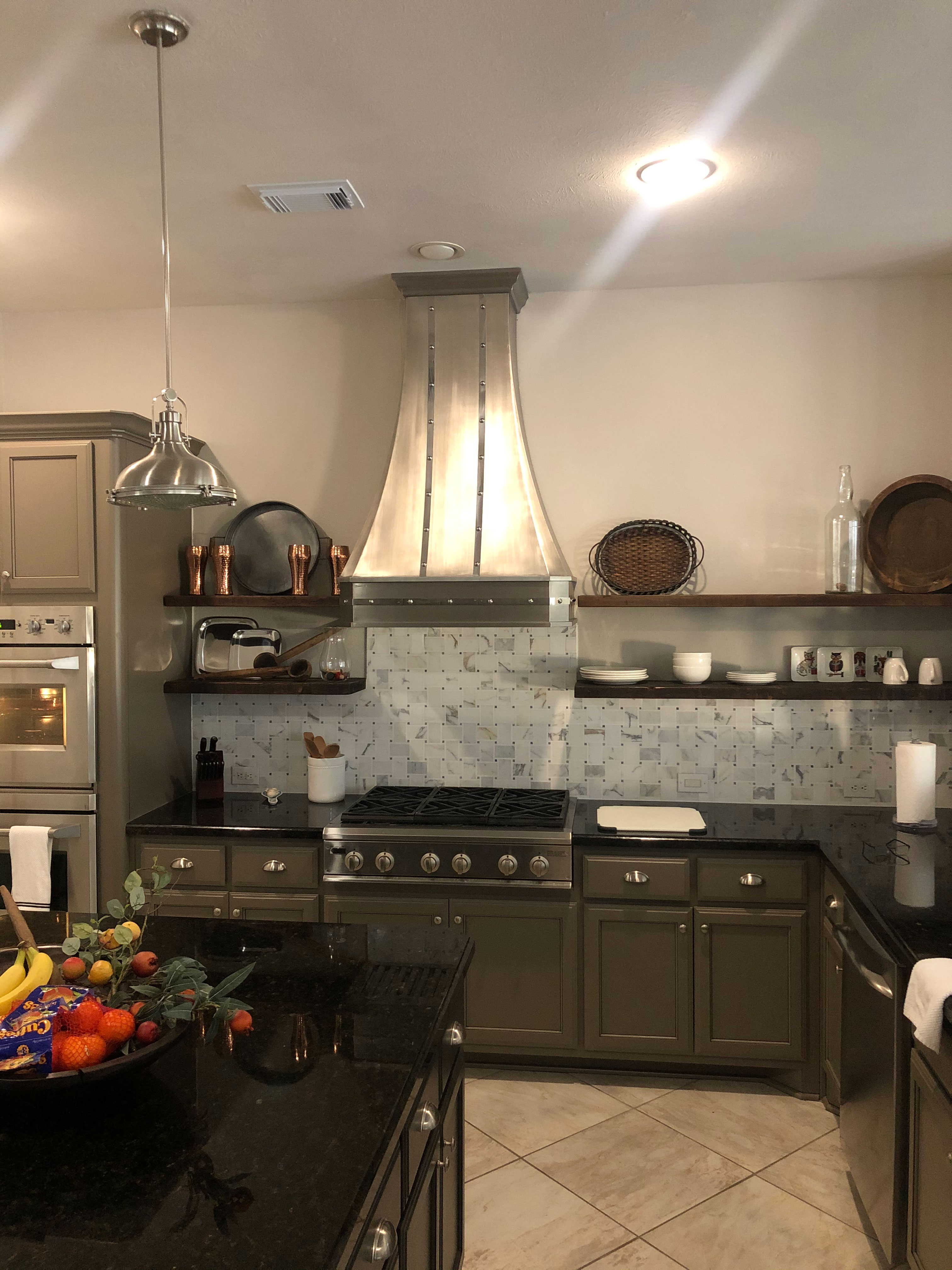 Stainless steel range hood in a kitchen with gray cabinets. World CopperSmith