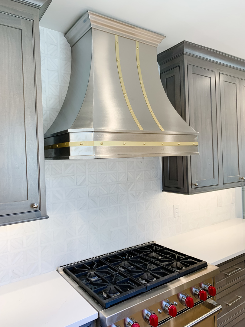 Stainless steel range hood in a white and chrome kitchen World CopperSmith