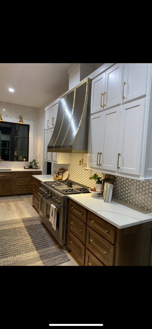 French design idea with range hood with brown cabinets, marble countertops, luxurious marble backsplash