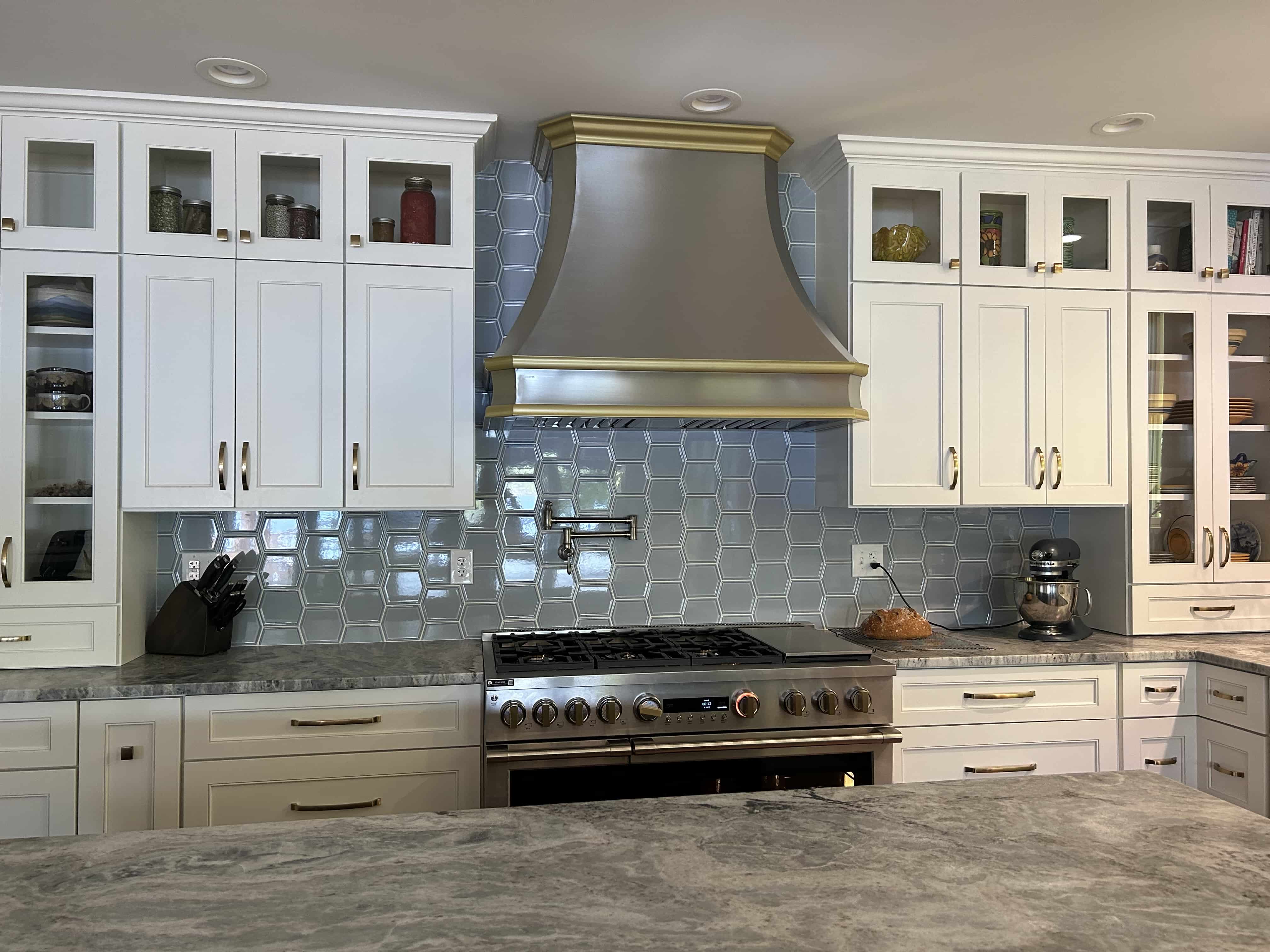 CopperSmith Classic CX9 Brushed Stainless Steel Kitchen Range Hood featuring white cabinets with gold details marble countertop and tile backsplash in a french style