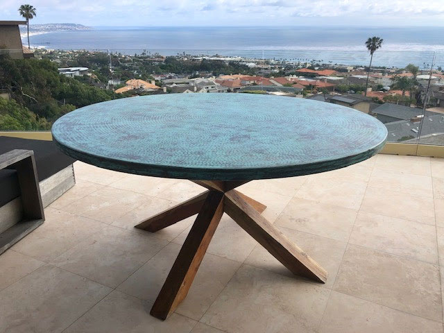 Round copper table with green patina on outdoor patio with tiles World CopperSmith