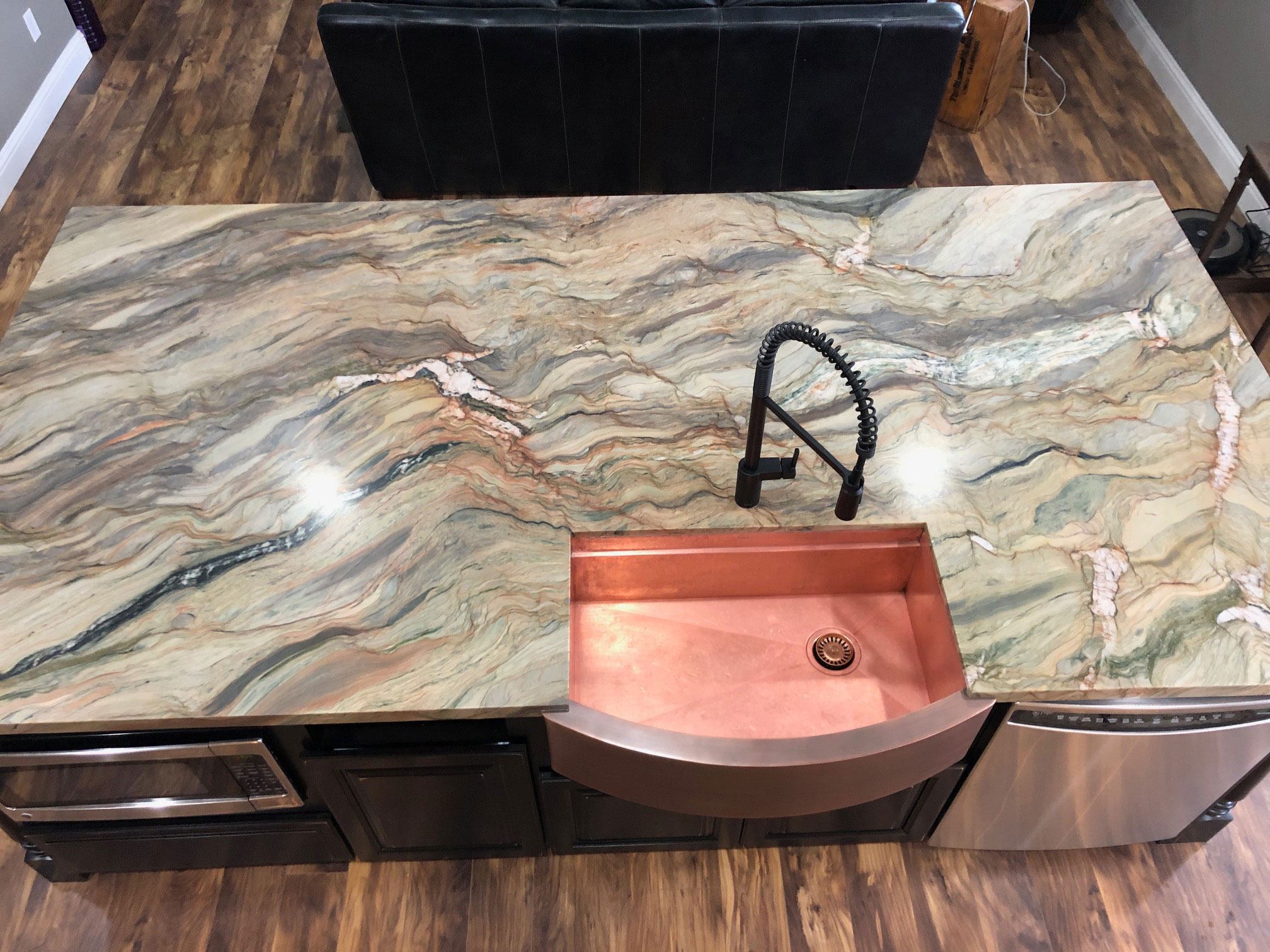 Copper apron sink in a kitchen with granite countertops and hardwood floors. World CopperSmith