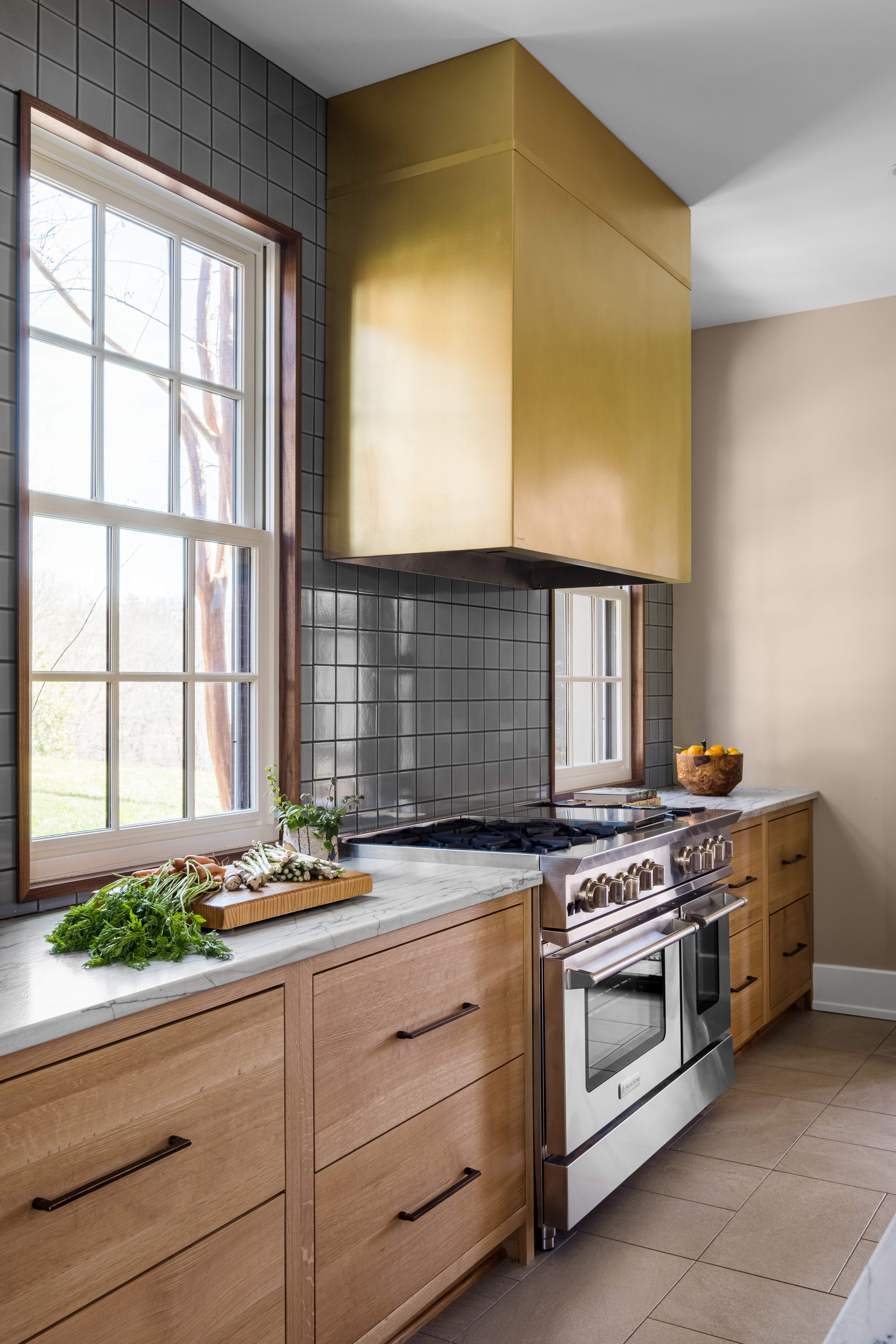 Featuring a range hood, kitchen design idea french-inspired elements, elegant brown kitchen cabinets, luxurious marble kitchen countertops, and marble backsplash