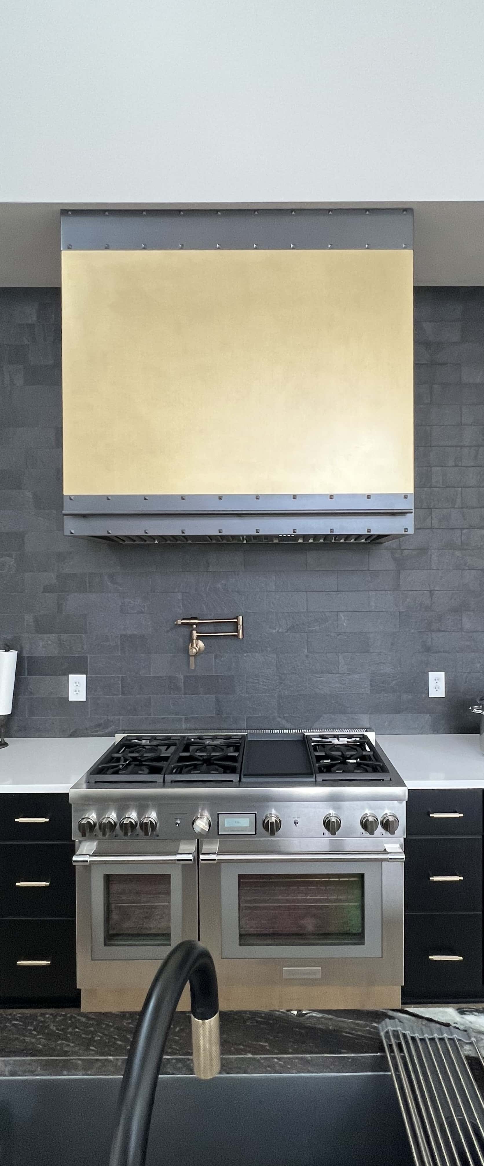 Range hood meet sleek sophistication, elevate space with striking black kitchen cabinets and pristine white kitchen countertops