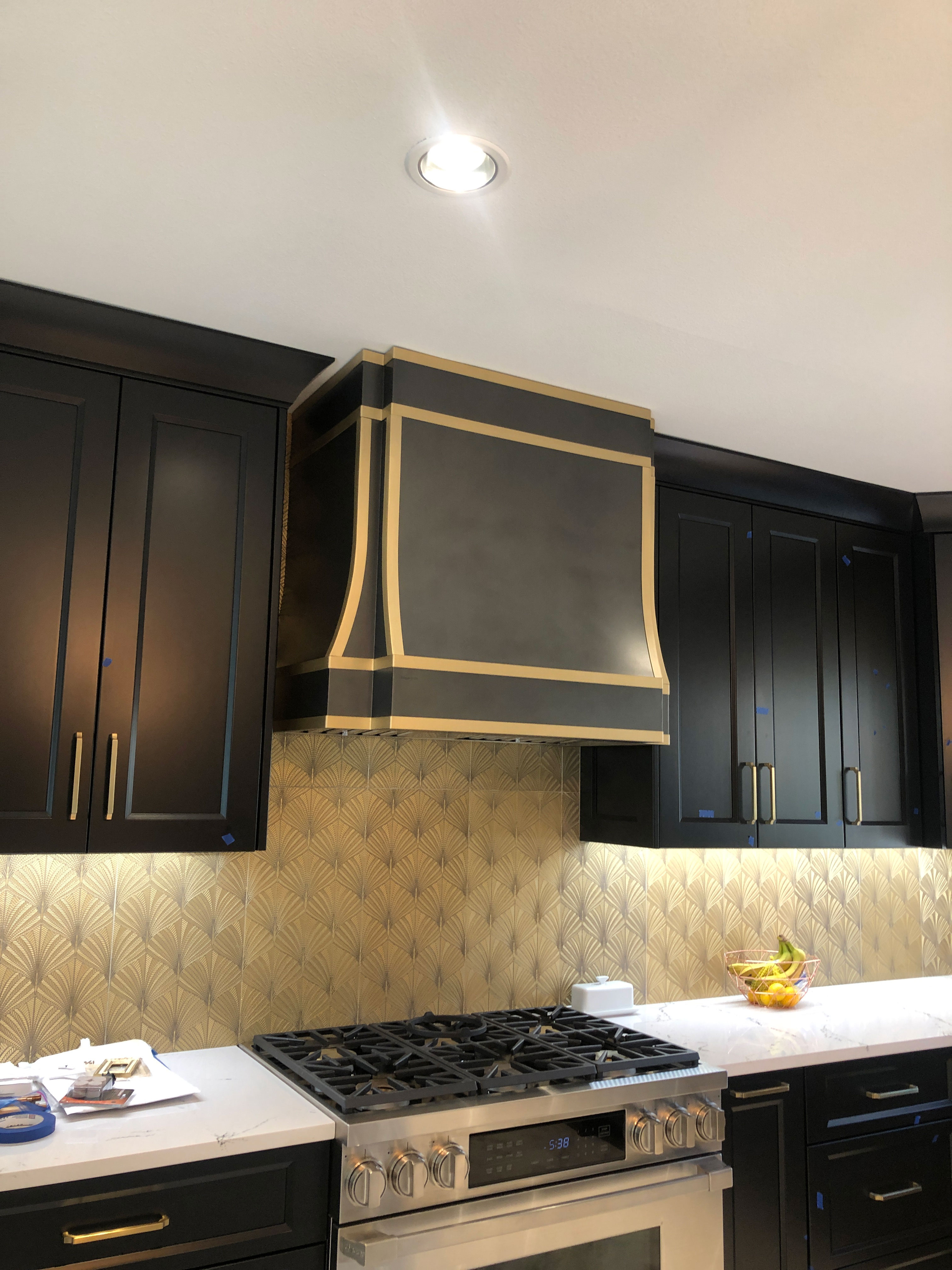 Kitchen design idea including range hood with grey kitchen cabinets, sleek white kitchen countertops andcaptivating copper backsplash