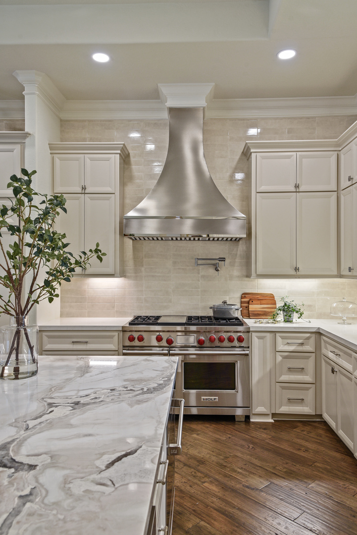 Stylish range hood options kitchen design idea with elegant french influences, beautiful white kitchen countertops, a luxurious marble backsplash