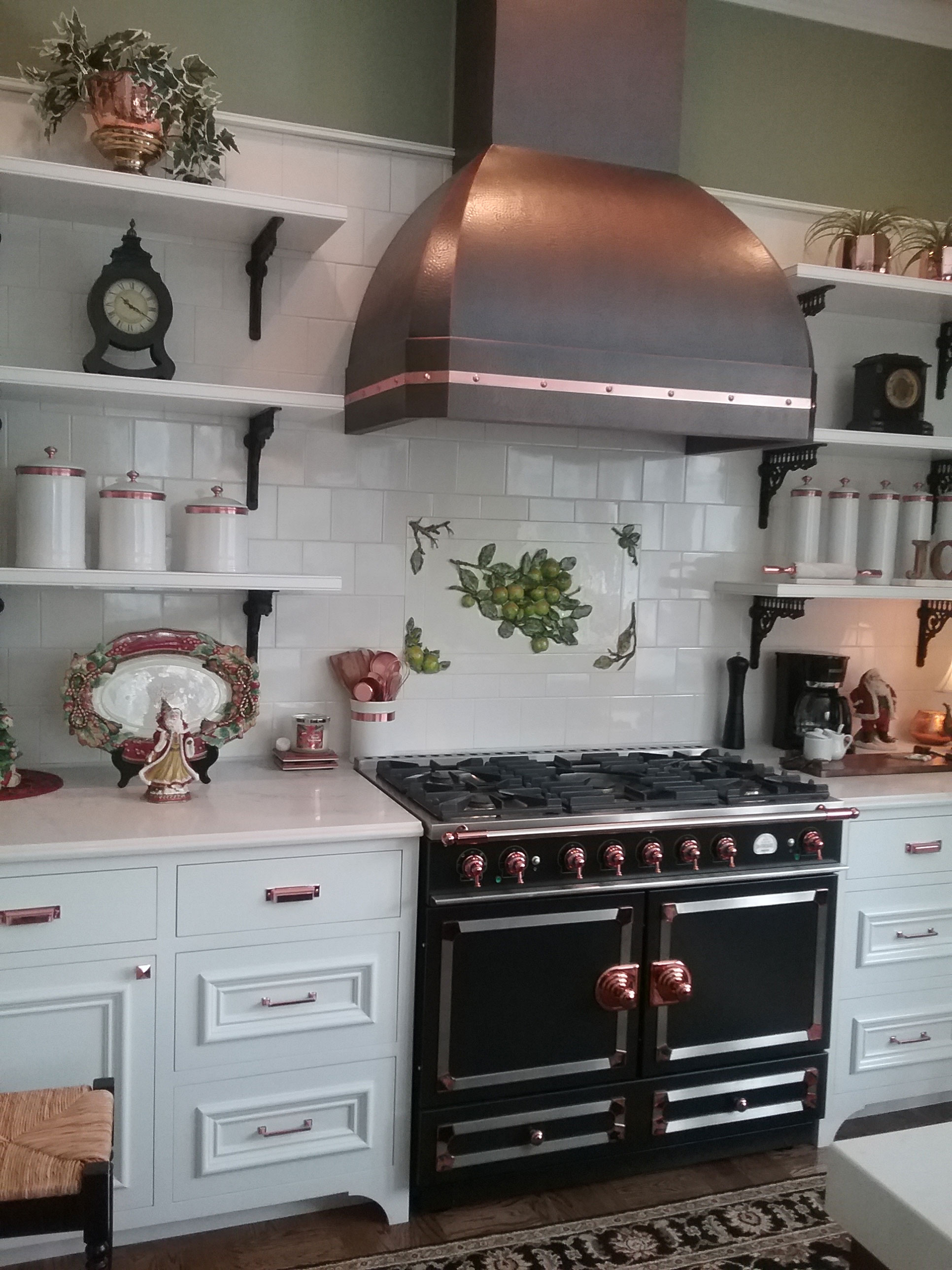 Copper range hood with unique dome shape in a kitchen with black appliances.