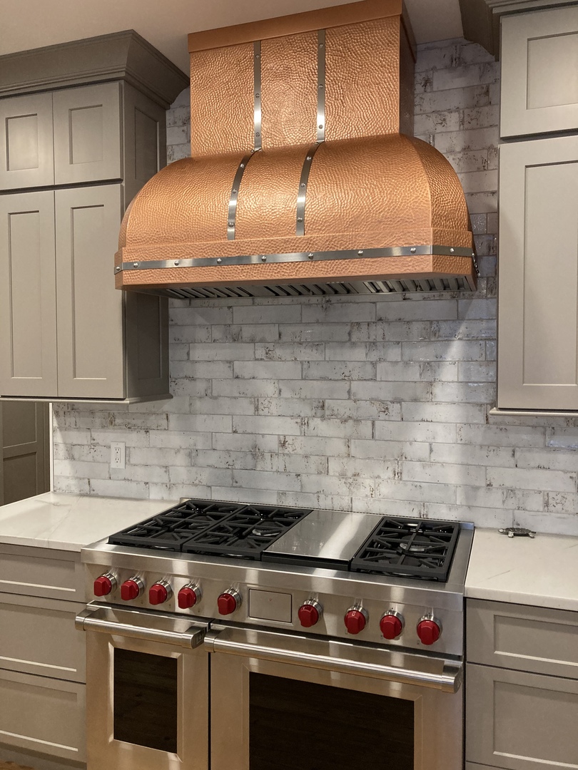 Kitchen design with white cabinets, marble countertops, brick backsplash, enhanced by innovative range hood for a stylish and inviting culinary space