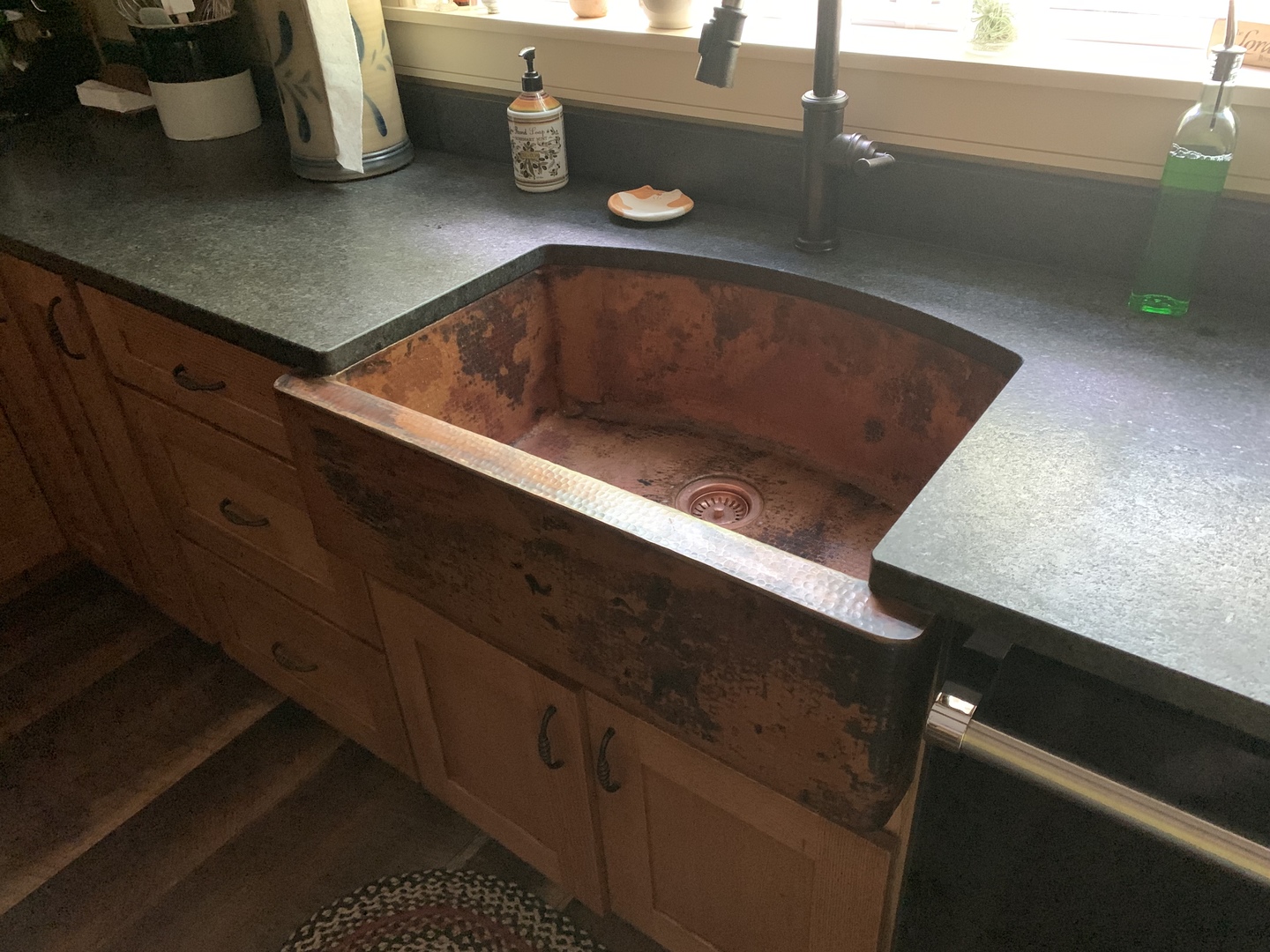 Copper apron sink with dark countertop and window World CopperSmith