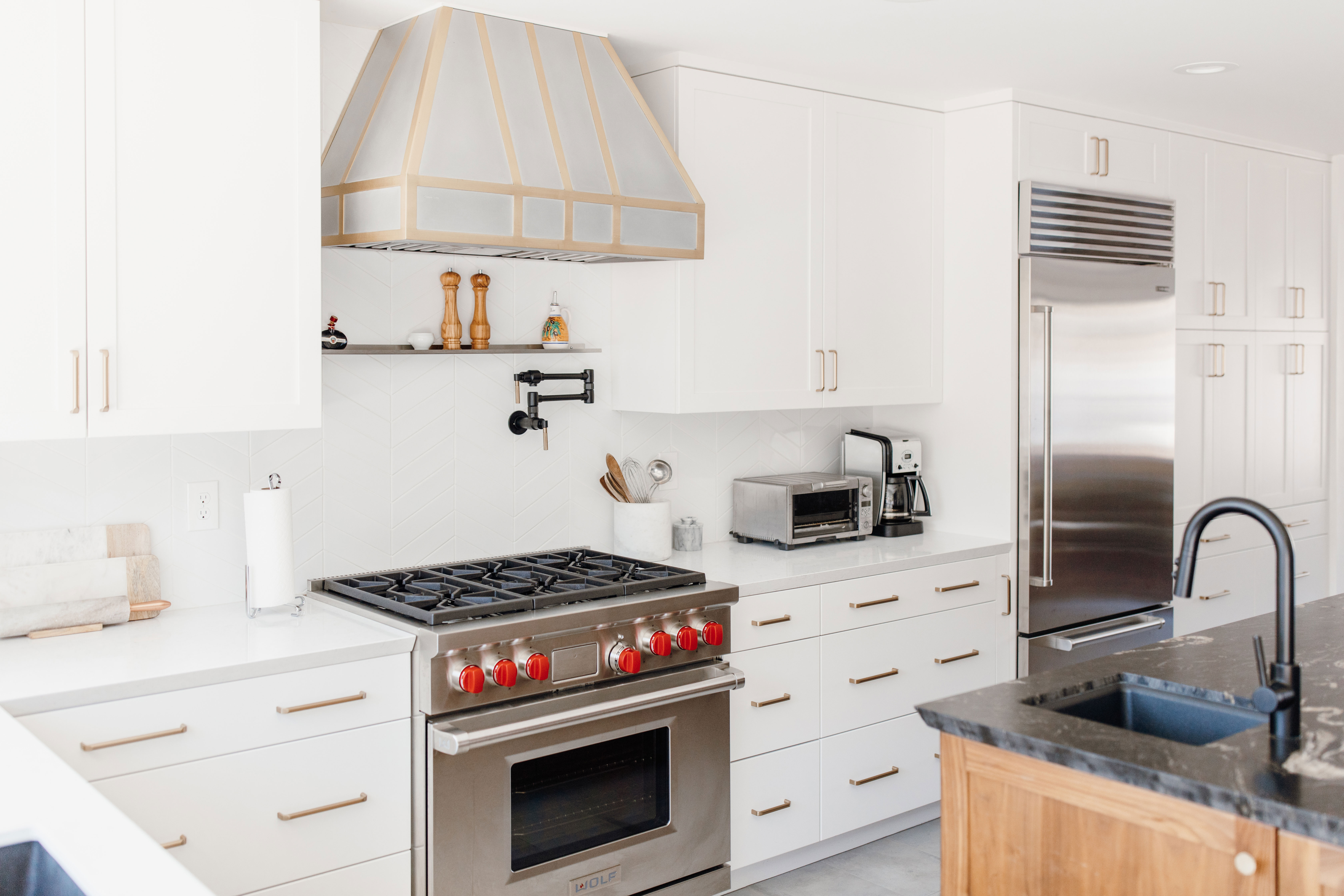 Beautiful kitchen design idea with stylish range hood, white kitchen cabinets, white kitchen countertops and marble backsplash