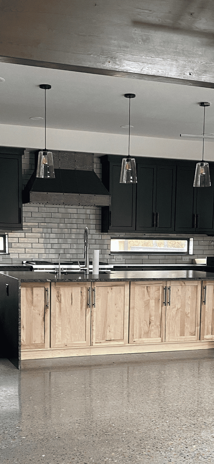 CopperSmith MX3 Antique Copper Kitchen Range Hood in an industrial and elegant style kitchen with black and wood cabinets dark tile backsplash and black countertops