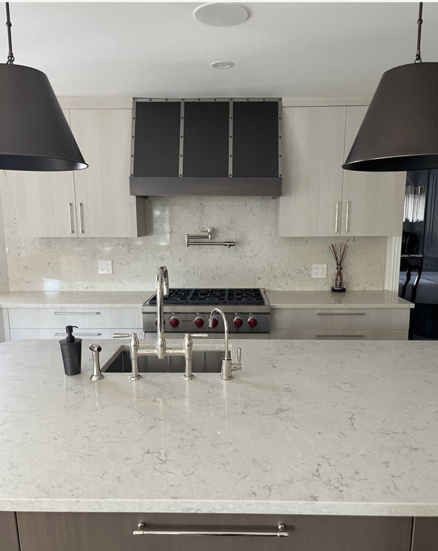 Coastal kitchen projects with a range of hood idea, stylish grey kitchen cabinets, sleek black kitchen countertops, marble backsplash
