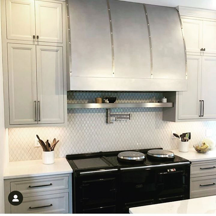 Aluminum range hood in a modern white kitchen with black stove World CopperSmith