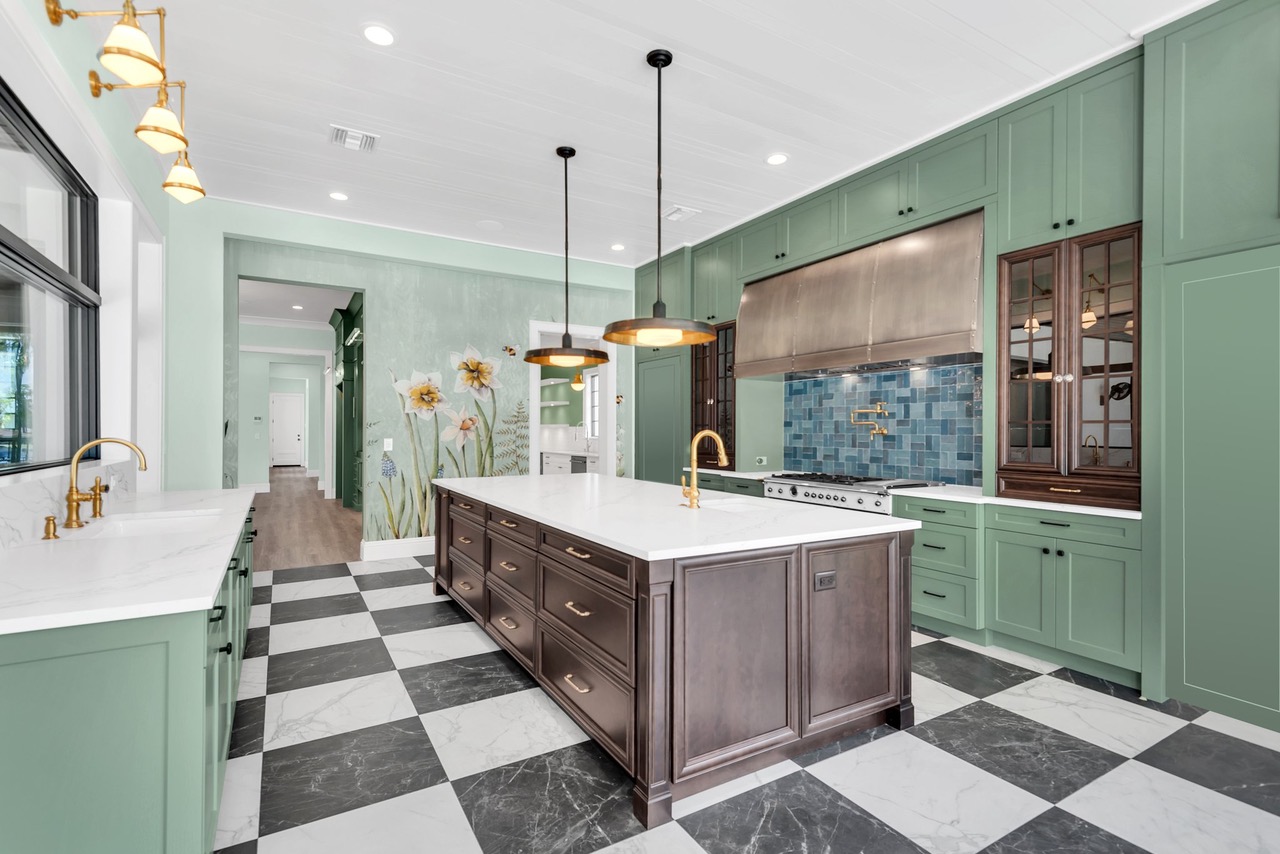 CopperSmith Premier PR4 Light Antique Brass Range Hood  in a Craftsman Style Kitchen with Green and wood cabinets white countertops and blue tile backsplash